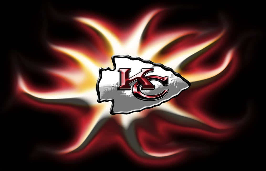 Kansas City Chiefs 桌布 壁紙 — 一個發光的堪薩斯城酋長隊標誌在黑暗背景下散發出火紅和金色的能量。