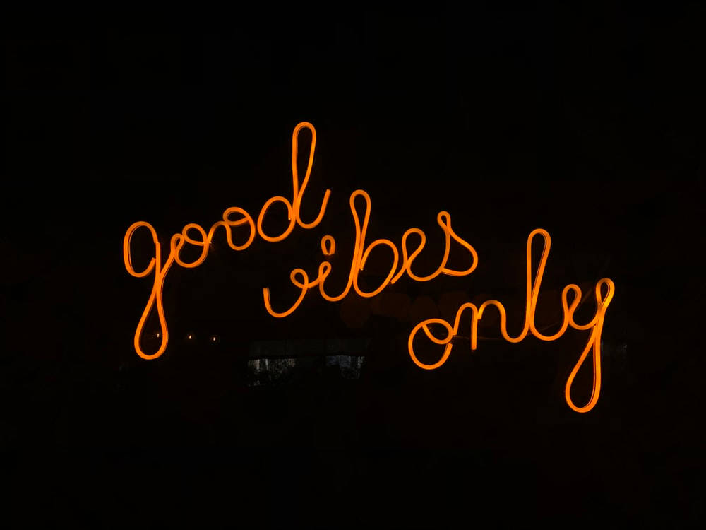 Good Vibes Only 桌布 壁紙 — 一個發光的橙色霓虹燈牌在漆黑背景上顯示 good vibes only。