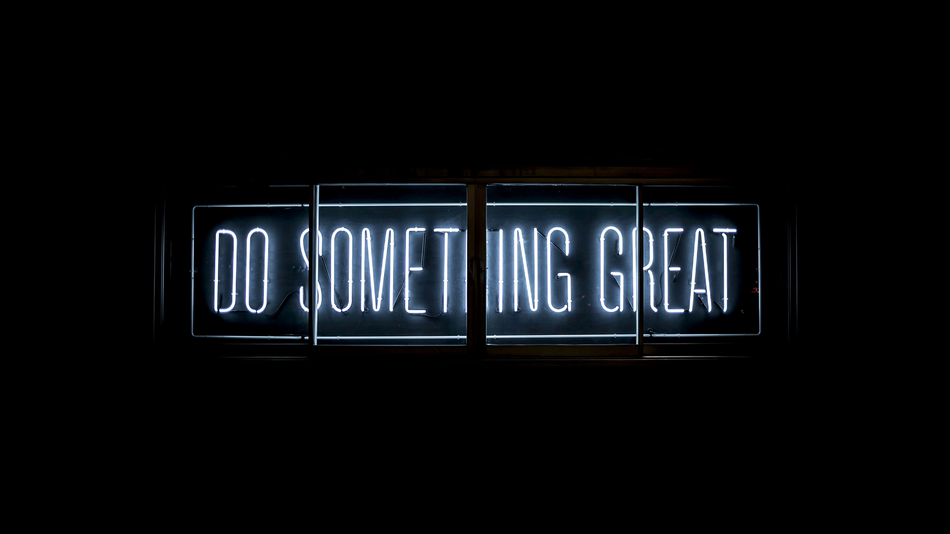 Motivational Quotes Black 桌布 壁紙 — 一個發光的白色霓虹燈牌，上面用粗體字寫著「DO SOMETHING GREAT」，背景是漆黑的。