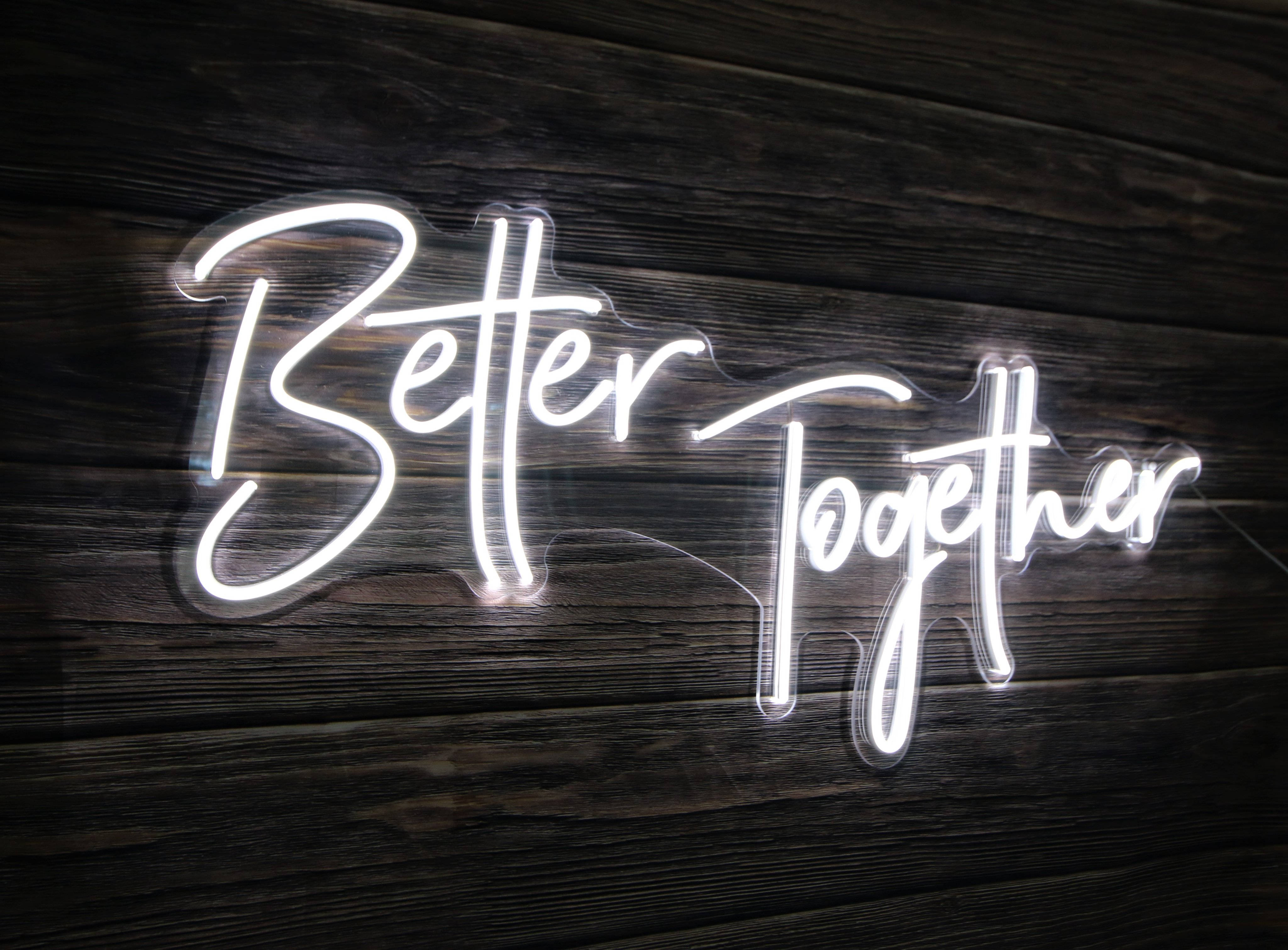 黑白 桌布 壁紙 — 一個發光的白色霓虹燈牌，以草書寫着「Better Together」，安裝在深色木板上。