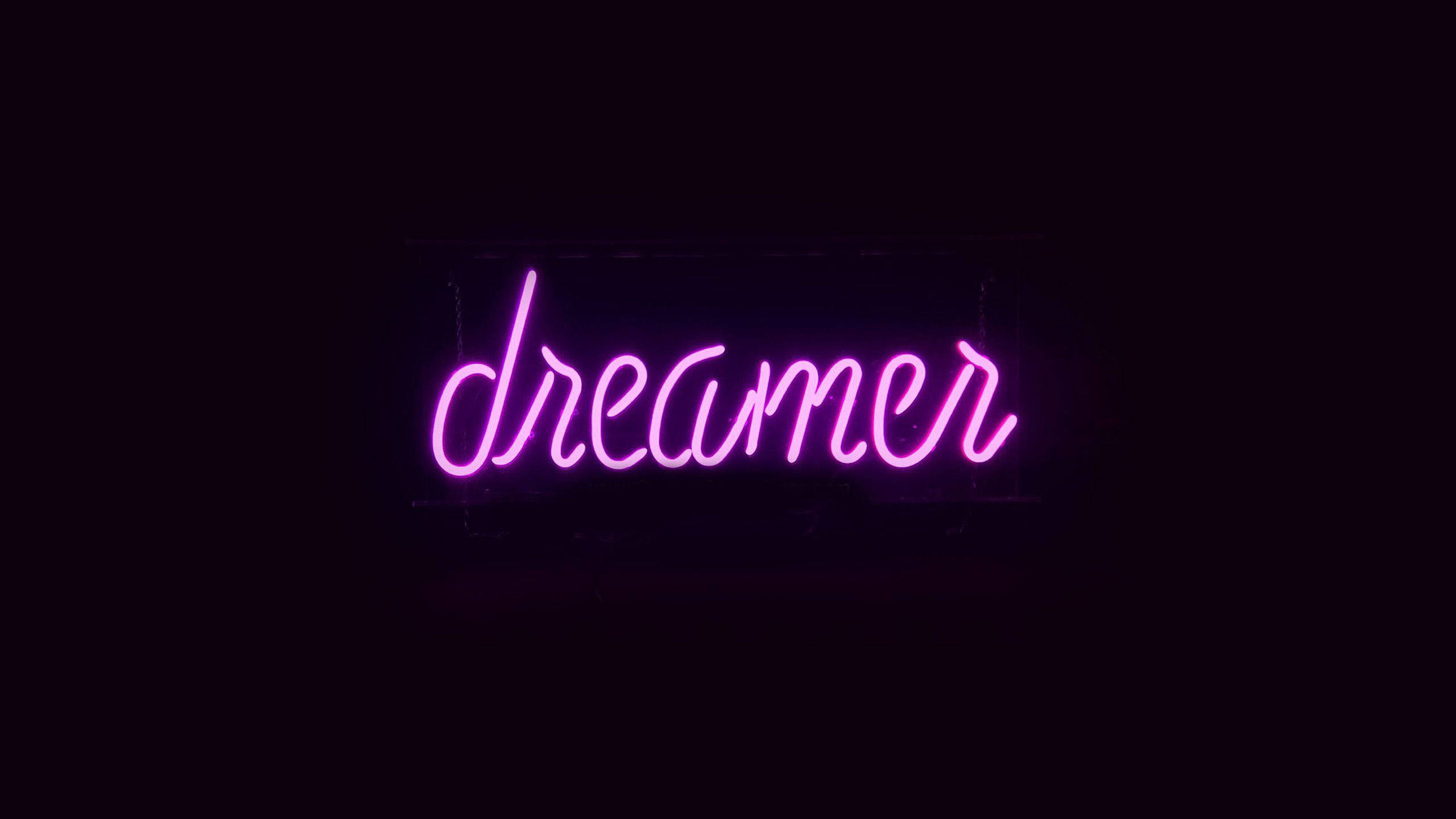 黑紫 桌布 壁紙 — 一個發光的粉紅色霓虹燈牌，拼出「dreamer」，在漆黑的背景上明亮地閃耀。