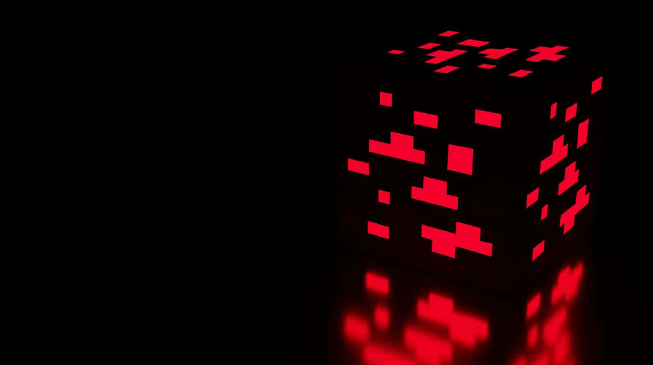 Minecraft Redstone 桌布 壁紙 — 一個發光的紅色像素化立方體在黑色虛空中發出數碼心跳，並帶有鏡面反射。