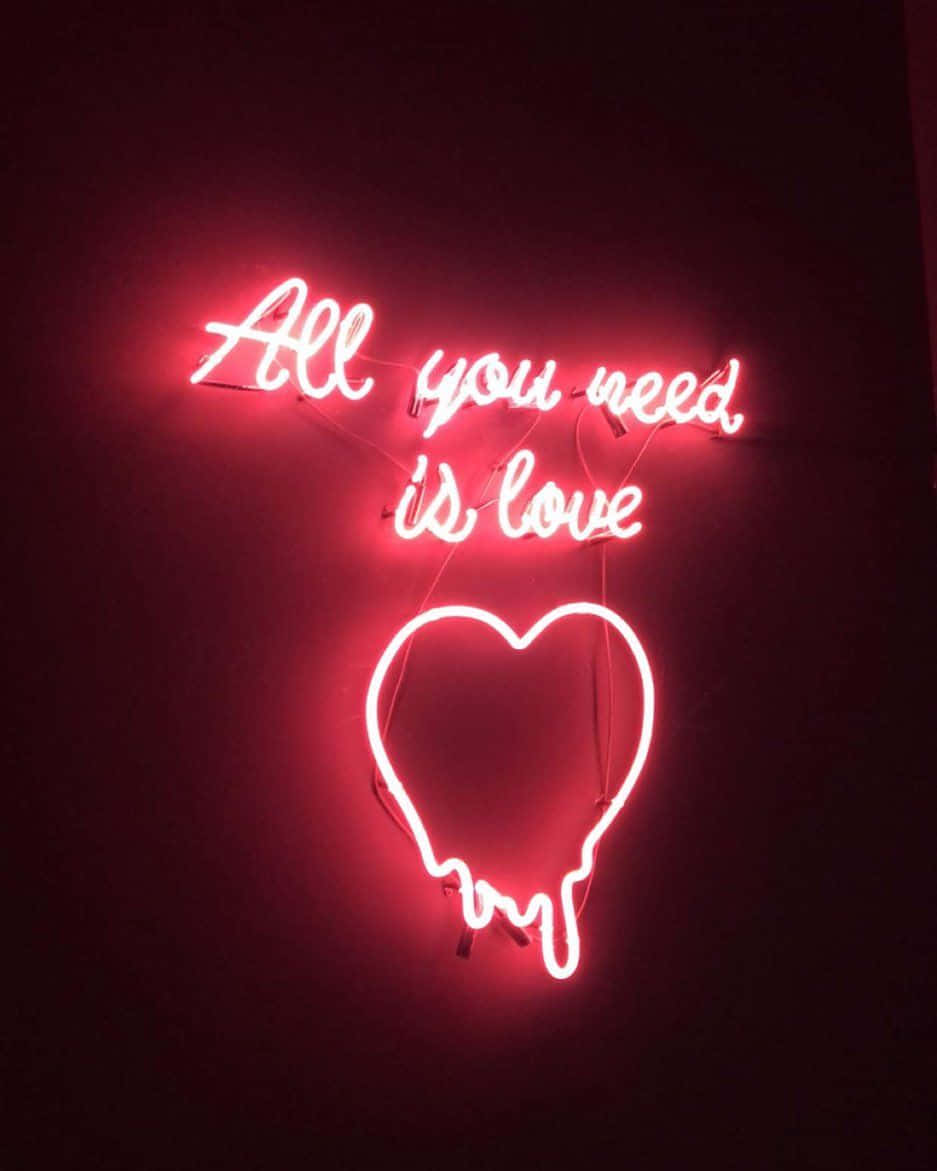愛戀風格 桌布 壁紙 — 一個發光的紅色霓虹燈牌，上面寫著「All you need is love」，位於一個正在融化的心形上方，背景是深色牆壁。