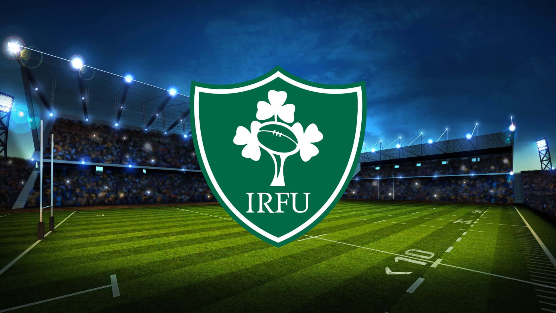 Ireland Rugby 桌布 壁紙 — 一個發光的綠色IRFU盾牌，帶有三葉草和橄欖球，在夜間照亮了明亮的橄欖球場。