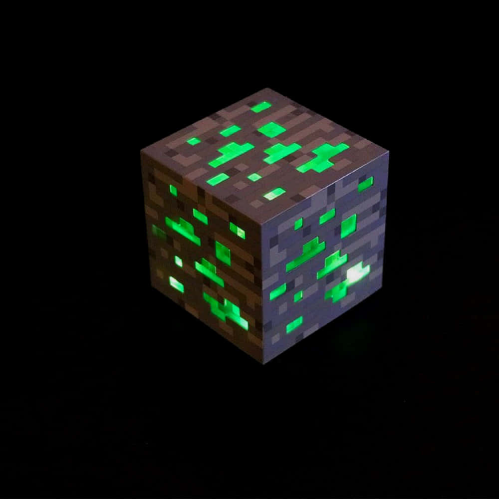 Minecraft Emeralds 桌布 壁紙 — 一個發光的綠色像素立方體，帶有泥土和石頭紋理，背景為黑色。