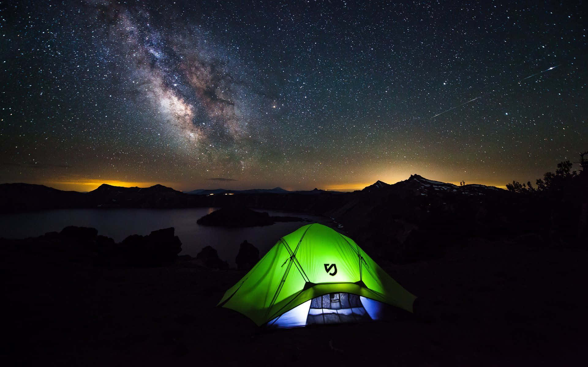 Beach Camping 桌布 壁紙 — 一個發光的綠色帳篷獨自矗立在令人驚嘆的星空下，銀河在黑暗的湖泊上空拱起。