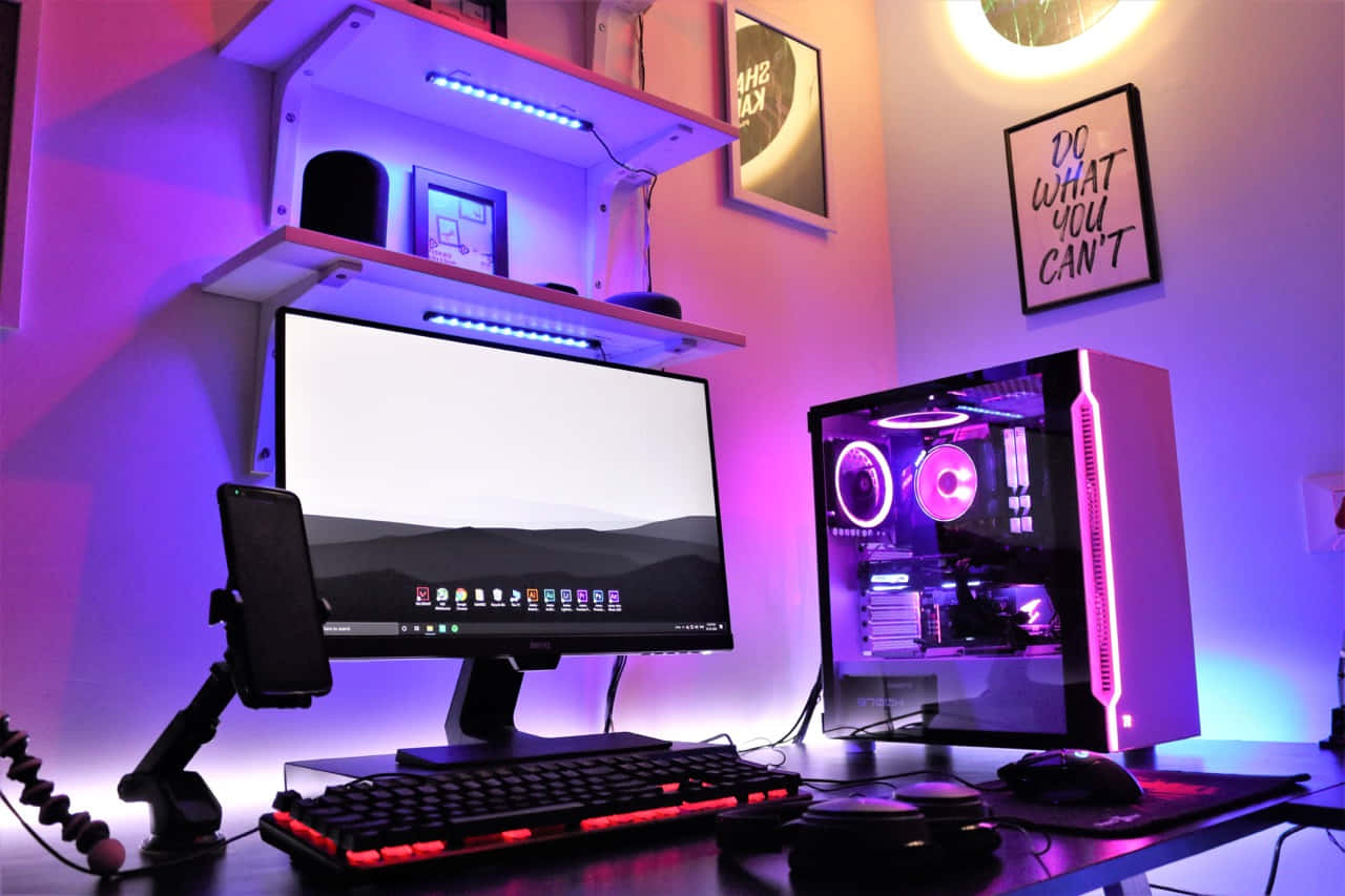 Gaming Pc Setup 桌布 壁紙 — 一個發光的遊戲設置，配有紫色和粉紅色的LED燈，照亮了一張帶有顯示器、鍵盤、滑鼠和透明電腦機箱的桌子。