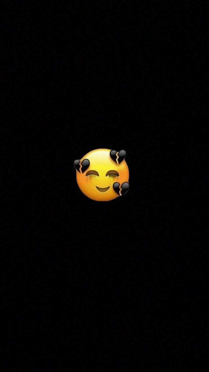 Black Emoji 桌布 壁紙 — 一個發光的黃色惡魔表情符號，帶有破裂的角和頑皮的笑容，獨自漂浮在純黑色背景上。