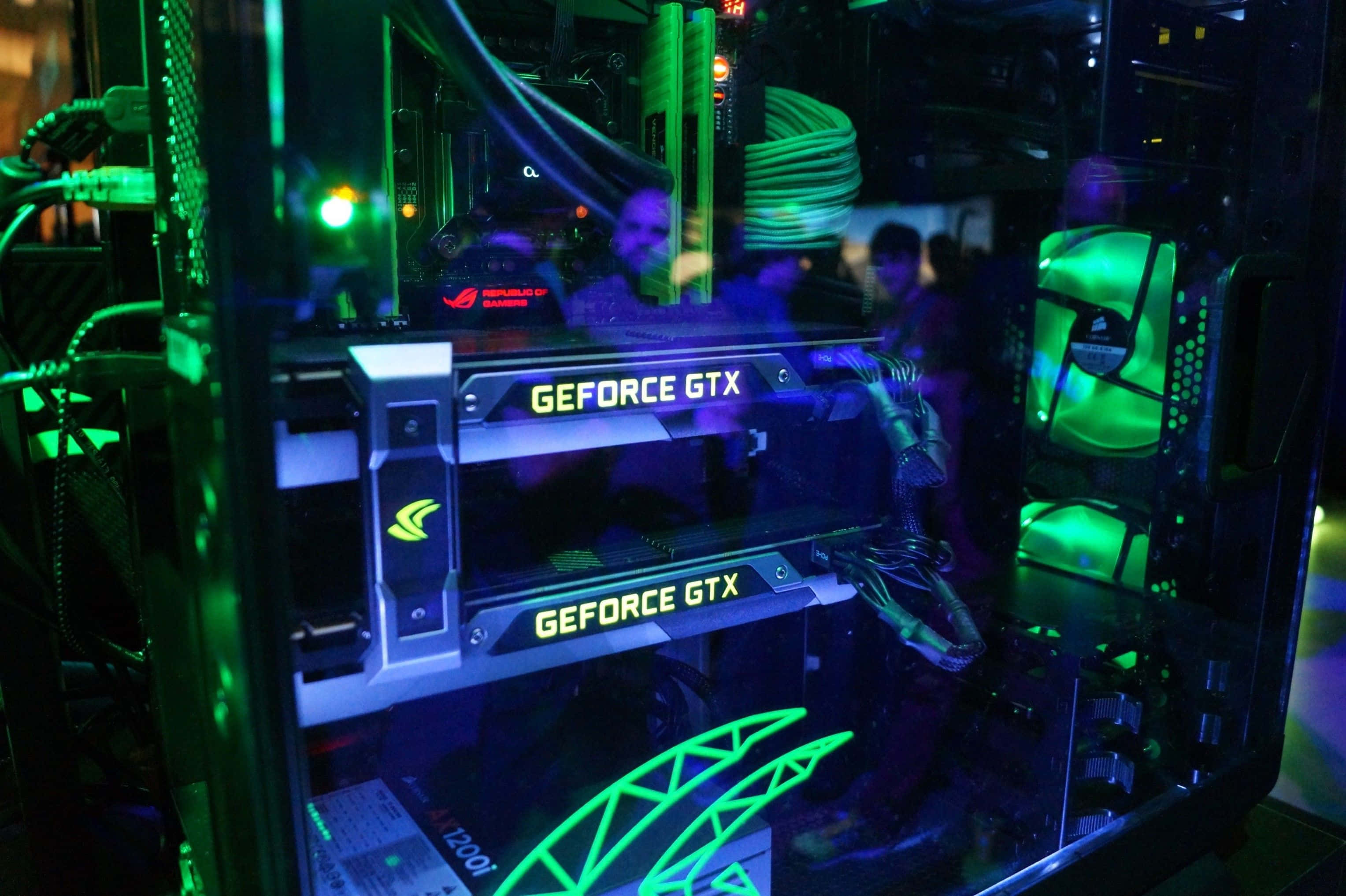 4K Graphics Cards 桌布 壁紙 — 一個發光綠色和藍色的自訂PC機箱展示了兩張GeForce GTX顯示卡，帶有鮮豔的LED燈光和可見的內部組件。