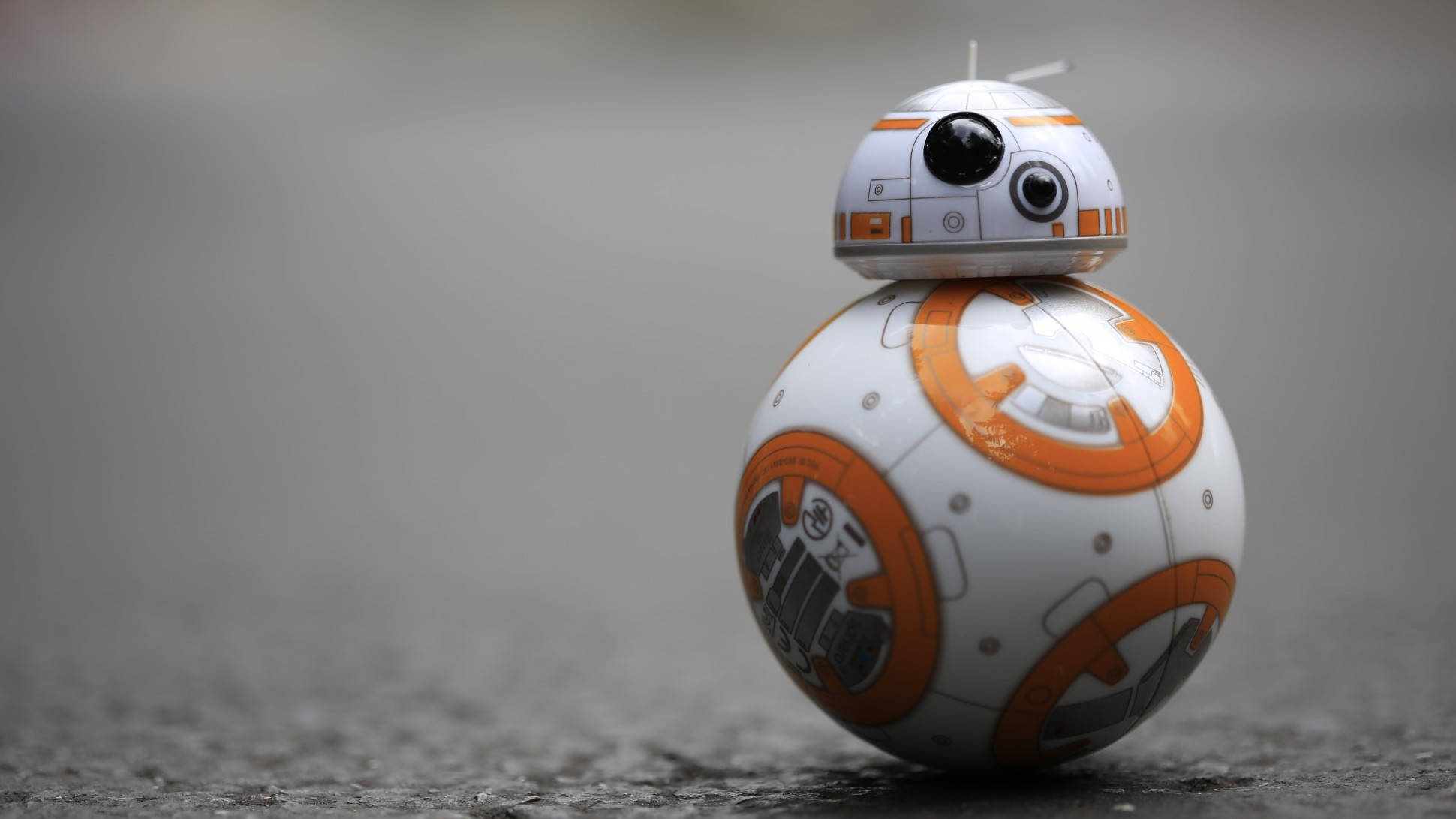 機械人 桌布 壁紙 — 一個白色和橙色的BB-8機械人站在灰色混凝土表面上，景深較淺。
