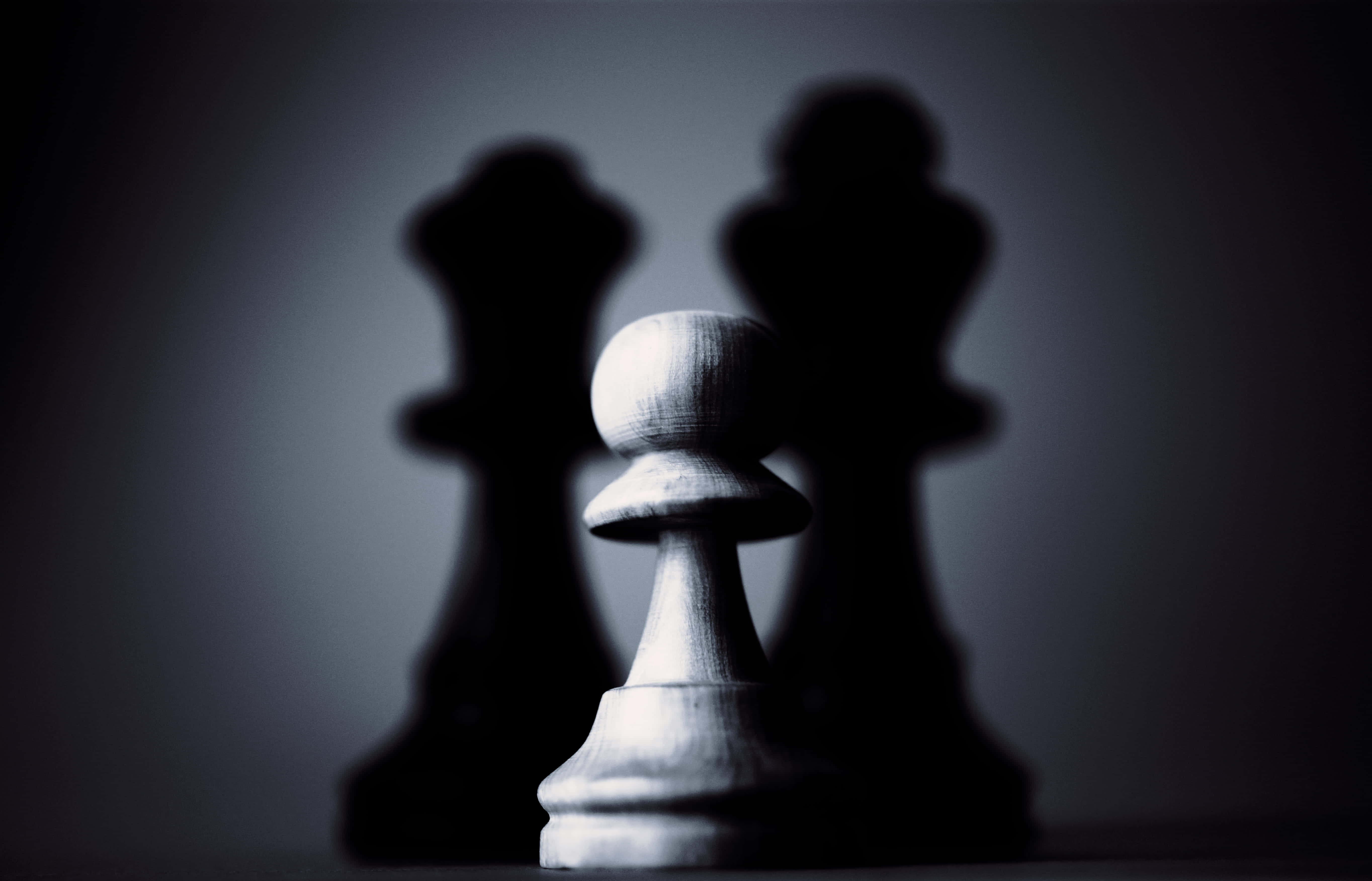shadow 桌布 壁紙 — 一個白色國際象棋兵在黑暗漸變背景上，對著模糊的黑色國王剪影，清晰對焦。