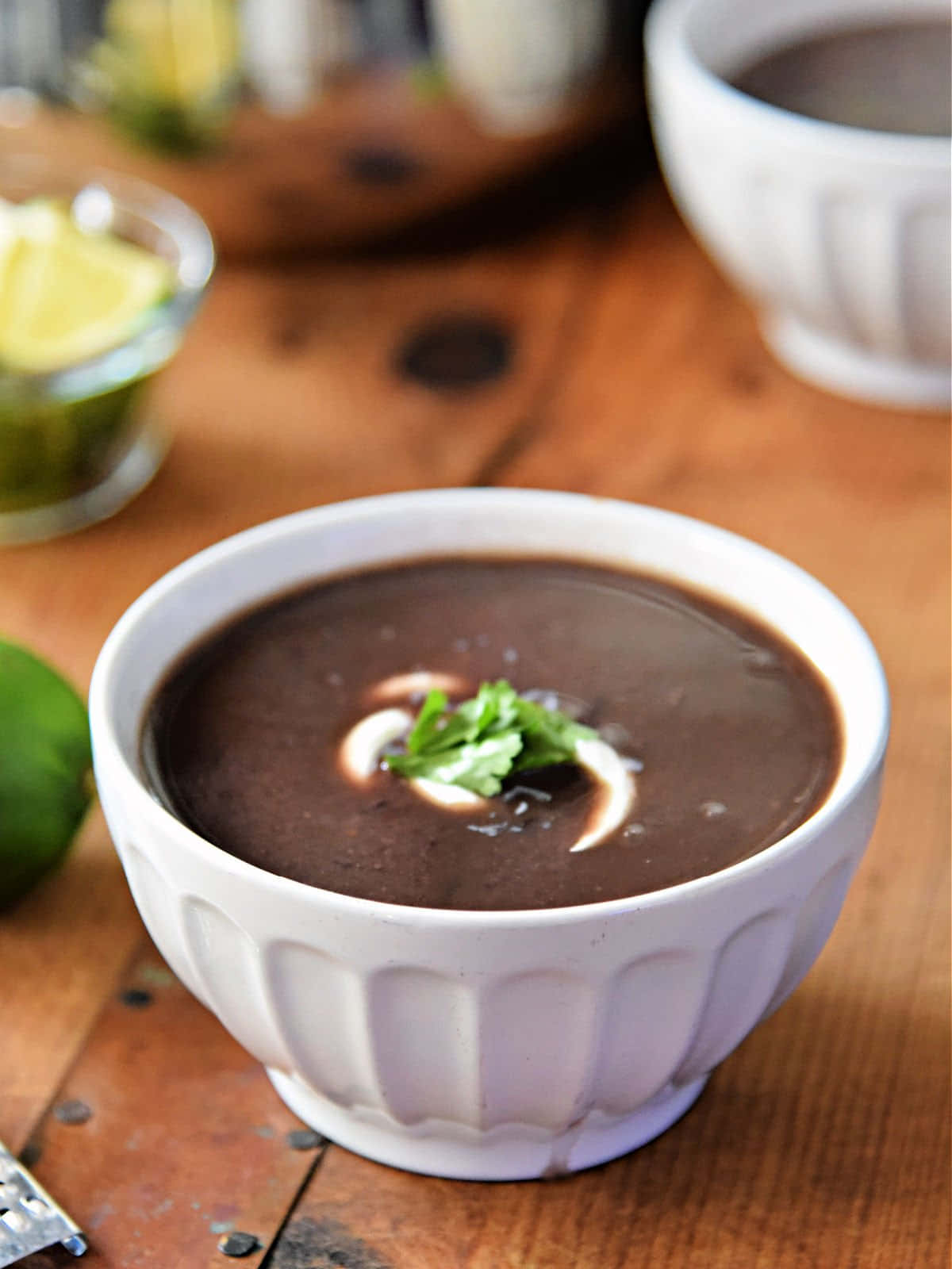 Black Bean Soup 桌布 壁紙 — 一個白色坑紋碗中的忌廉黑豆湯，飾以芫荽和忌廉，放在質樸的木桌上。