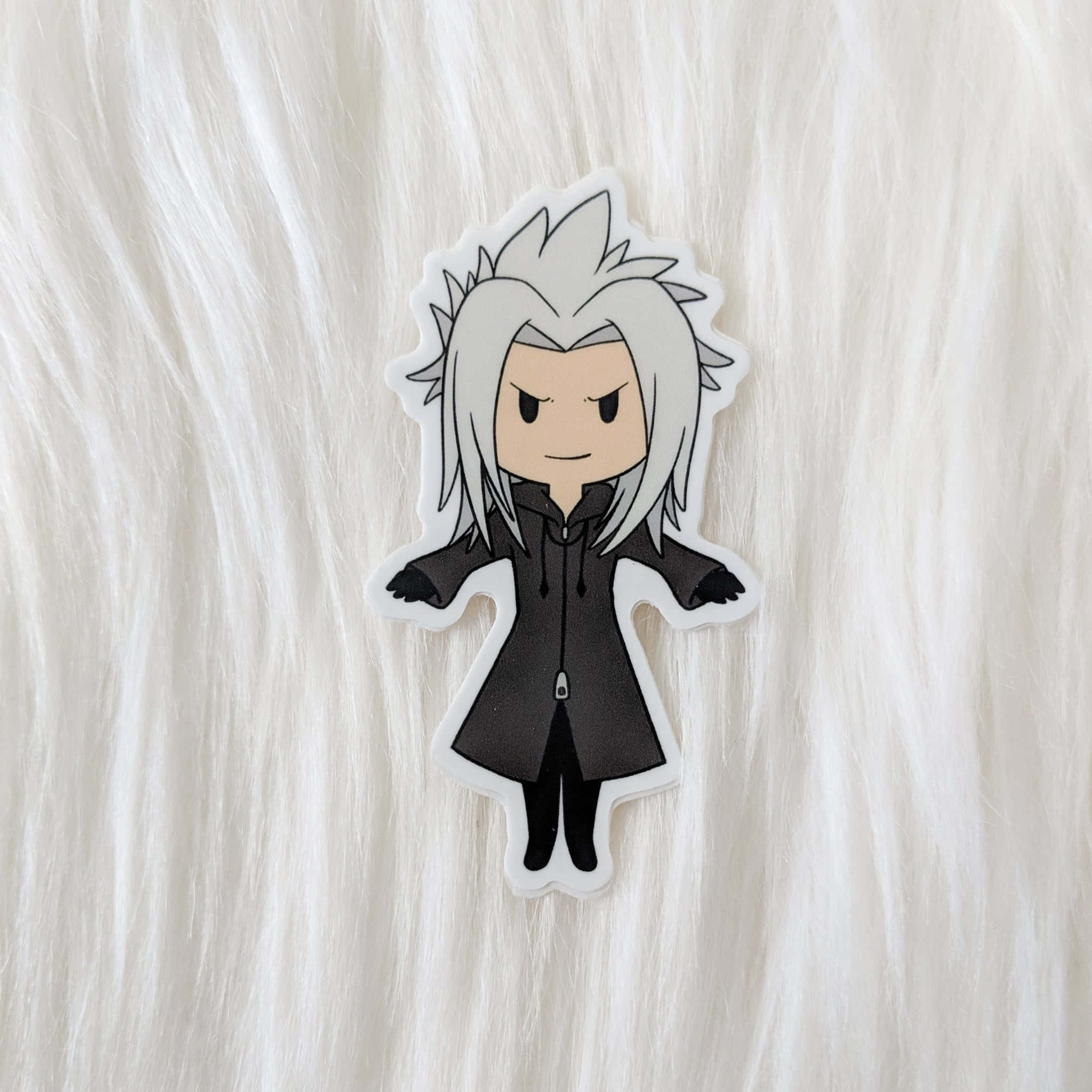 Kingdom Hearts Xemnas 桌布 壁紙 — 一個白色尖刺頭髮和黑色外套角色的Q版動漫貼紙，放在毛絨絨的白色表面上。