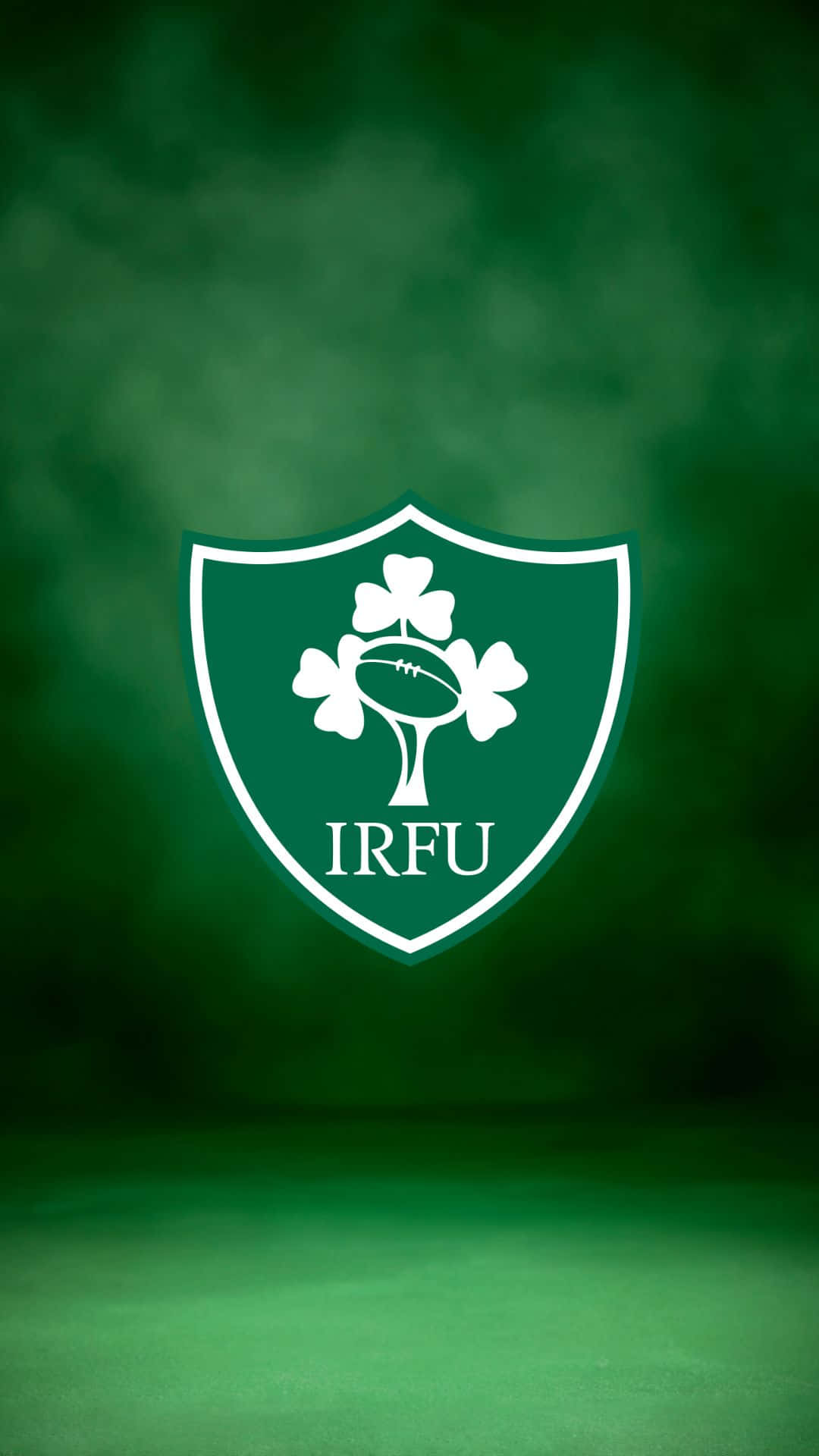 Ireland Rugby 桌布 壁紙 — 一個白色愛爾蘭欖球聯盟徽章，中央有三葉草和一個欖球，置於漸變綠色背景上。