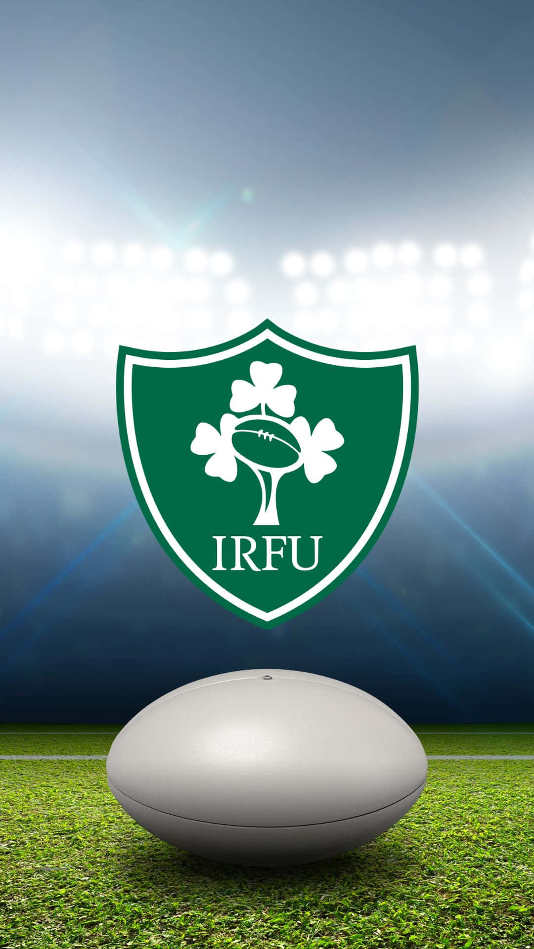 Ireland Rugby 桌布 壁紙 — 一個白色欖球放在充滿活力的綠色草地上，下方是愛爾蘭欖球聯盟標誌，被球場燈光照亮。
