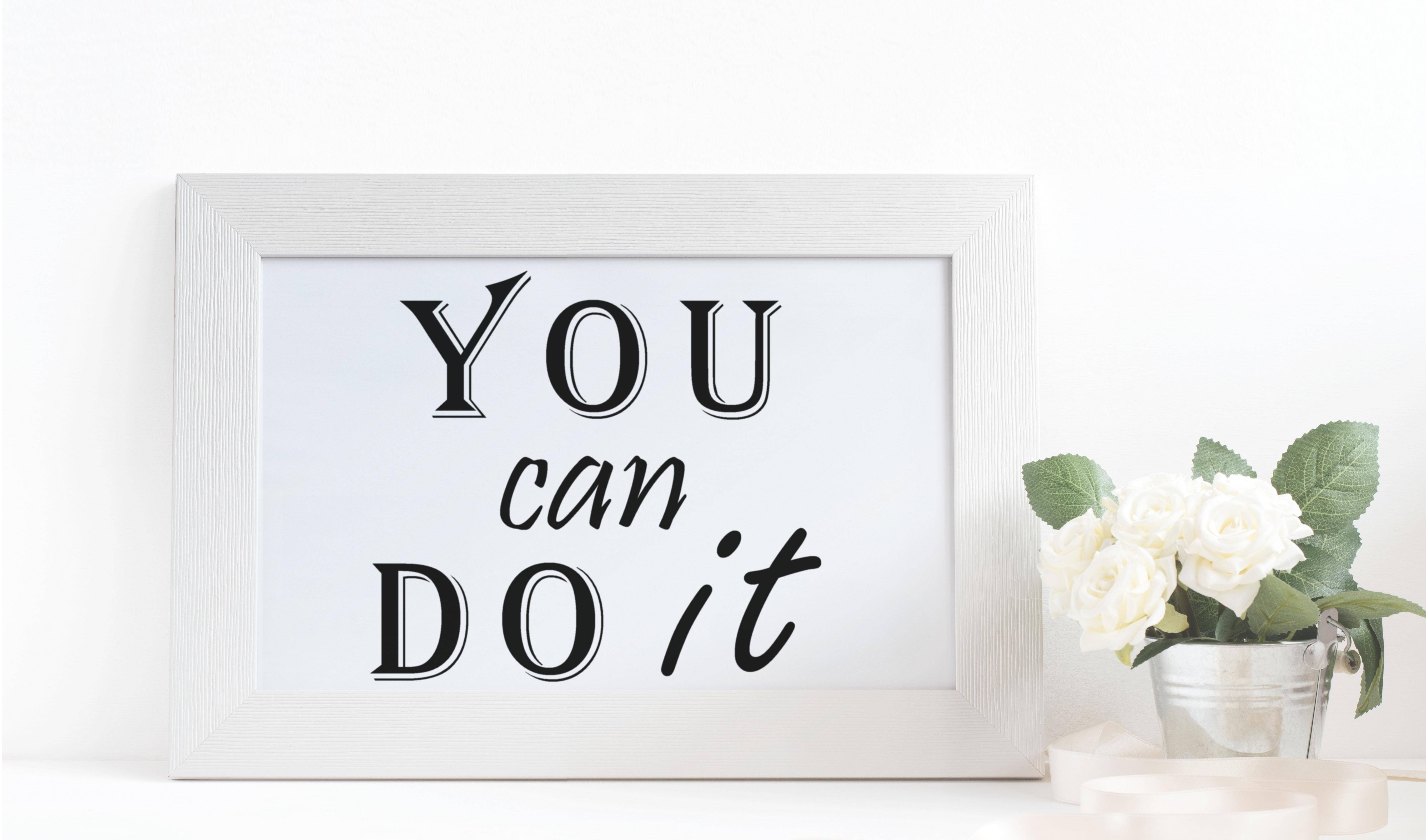 鼓舞人心的 桌布 壁紙 — 一個白色相框的勵志標語牌，上面寫著「YOU can DO it」，旁邊放著一桶白玫瑰，置於潔白的表面上。