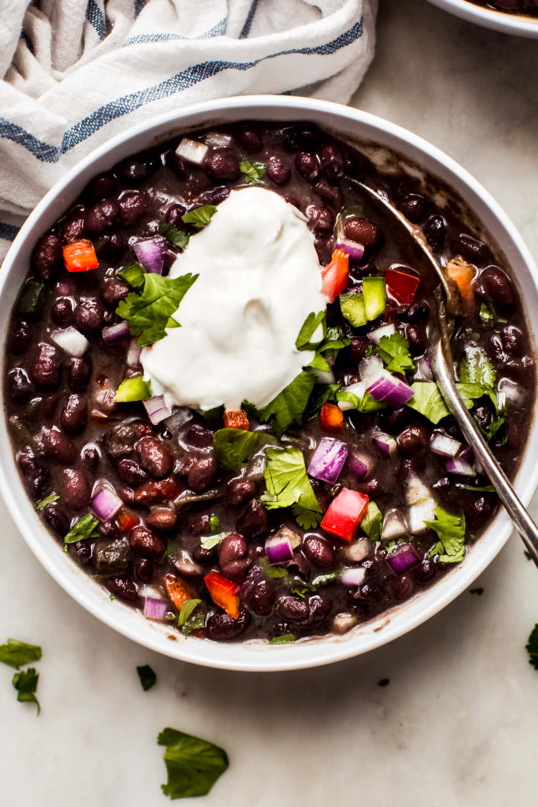 Black Bean Soup 桌布 壁紙 — 一個白色碗裝滿黑豆，上面放有酸奶油、芫荽和切粒蔬菜。