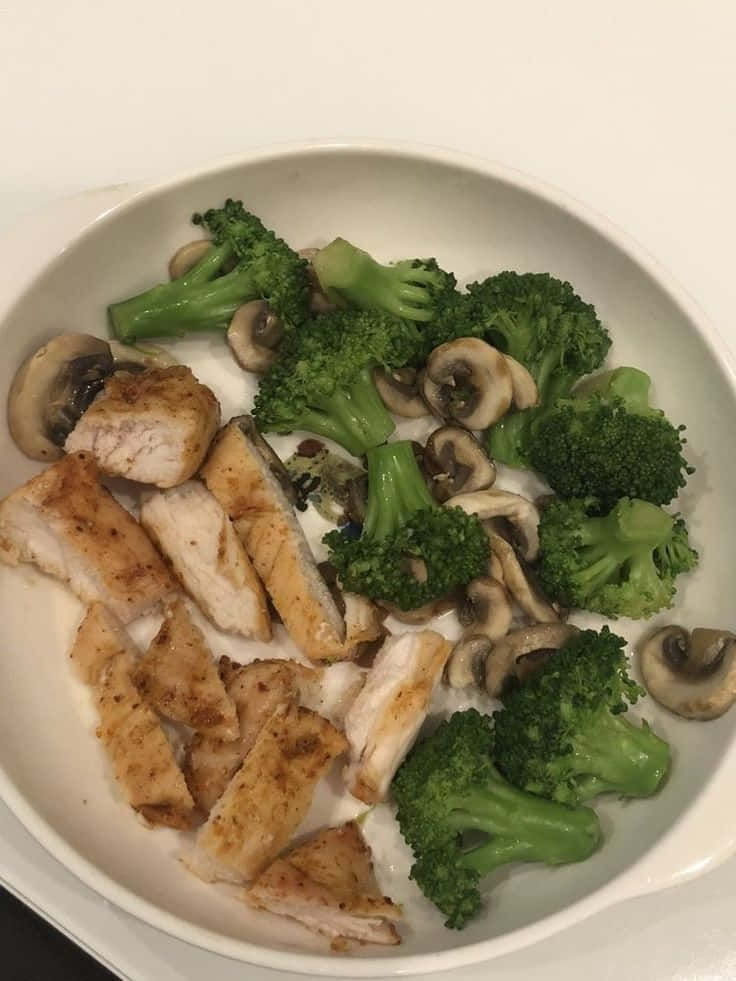 Minimalist Food 桌布 壁紙 — 一個白色碗裡盛著嫩滑的烤雞肉條，搭配鮮綠的西蘭花小朵和炒蘑菇。