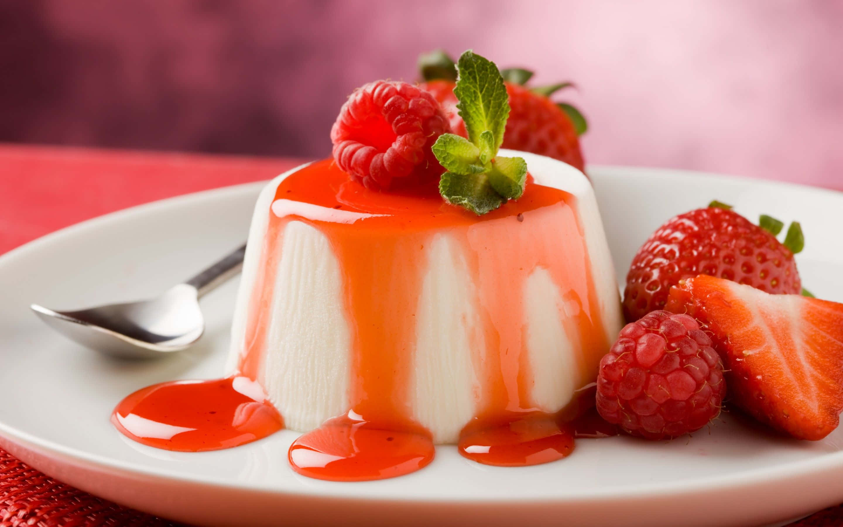 Spring Desserts 桌布 壁紙 — 一個白色碟上，有 creamy 白色意式奶凍，淋上亮澤紅色草莓醬，並以新鮮莓果和薄荷裝飾。