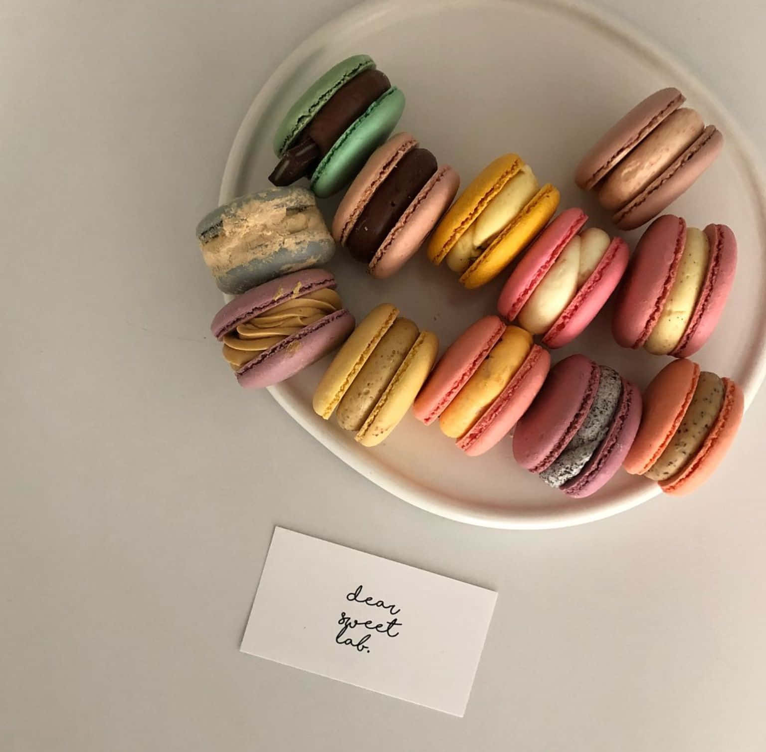 french 桌布 壁紙 — 一個白色碟子上放著色彩繽紛的馬卡龍，排列成半圓形，還有一張手寫便條寫著 dear sweet lab。