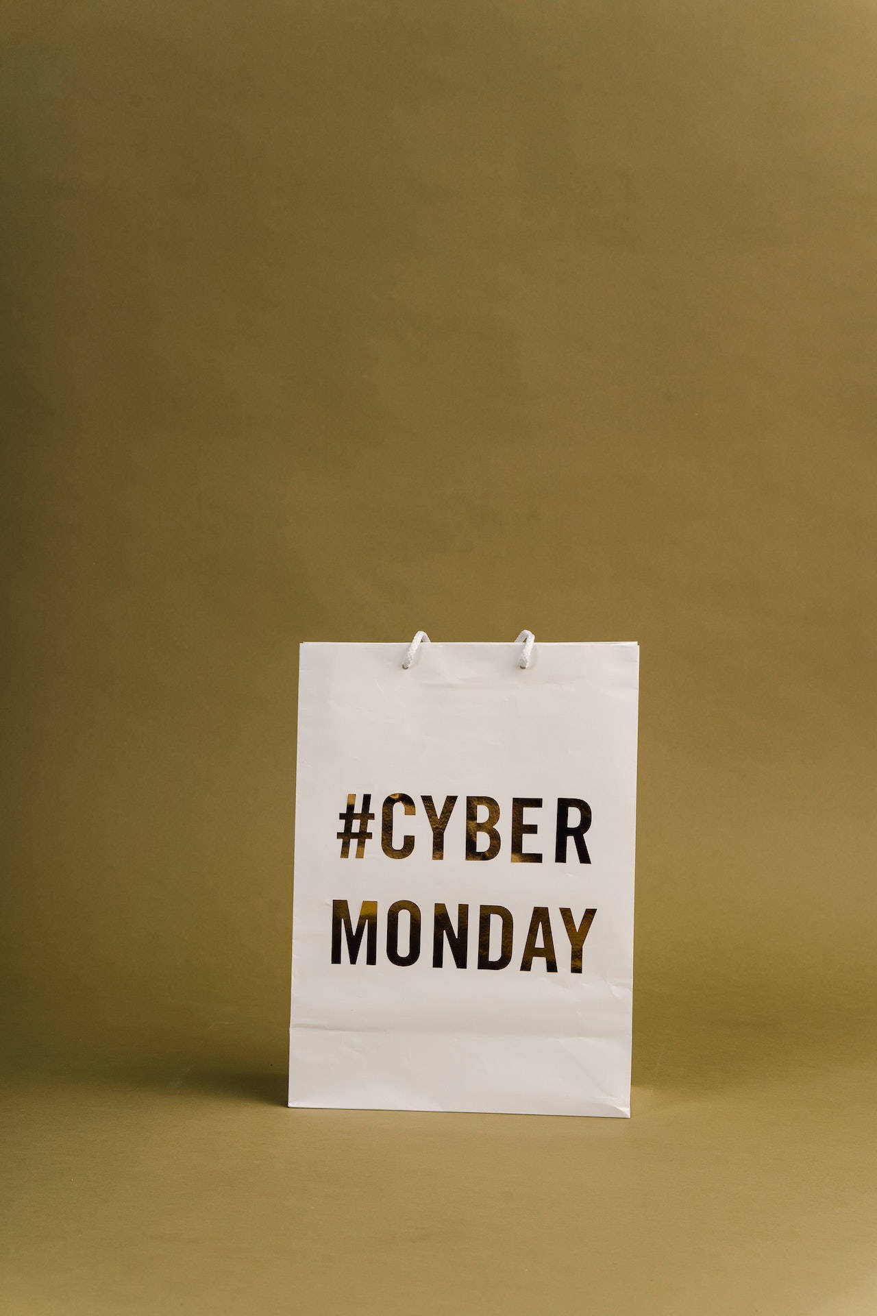 Monday 桌布 壁紙 — 一個白色紙購物袋，上面有#CYBER MONDAY文字，置於純芥末黃色背景中央。