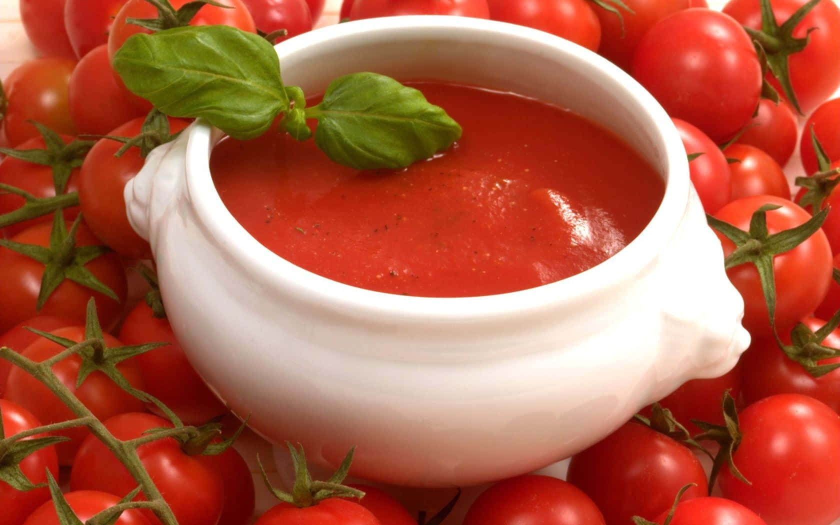 Red Sauce 桌布 壁紙 — 一個白色陶瓷碗，盛滿鮮紅番茄湯，飾以新鮮羅勒葉，周圍環繞著帶藤的成熟車厘茄。