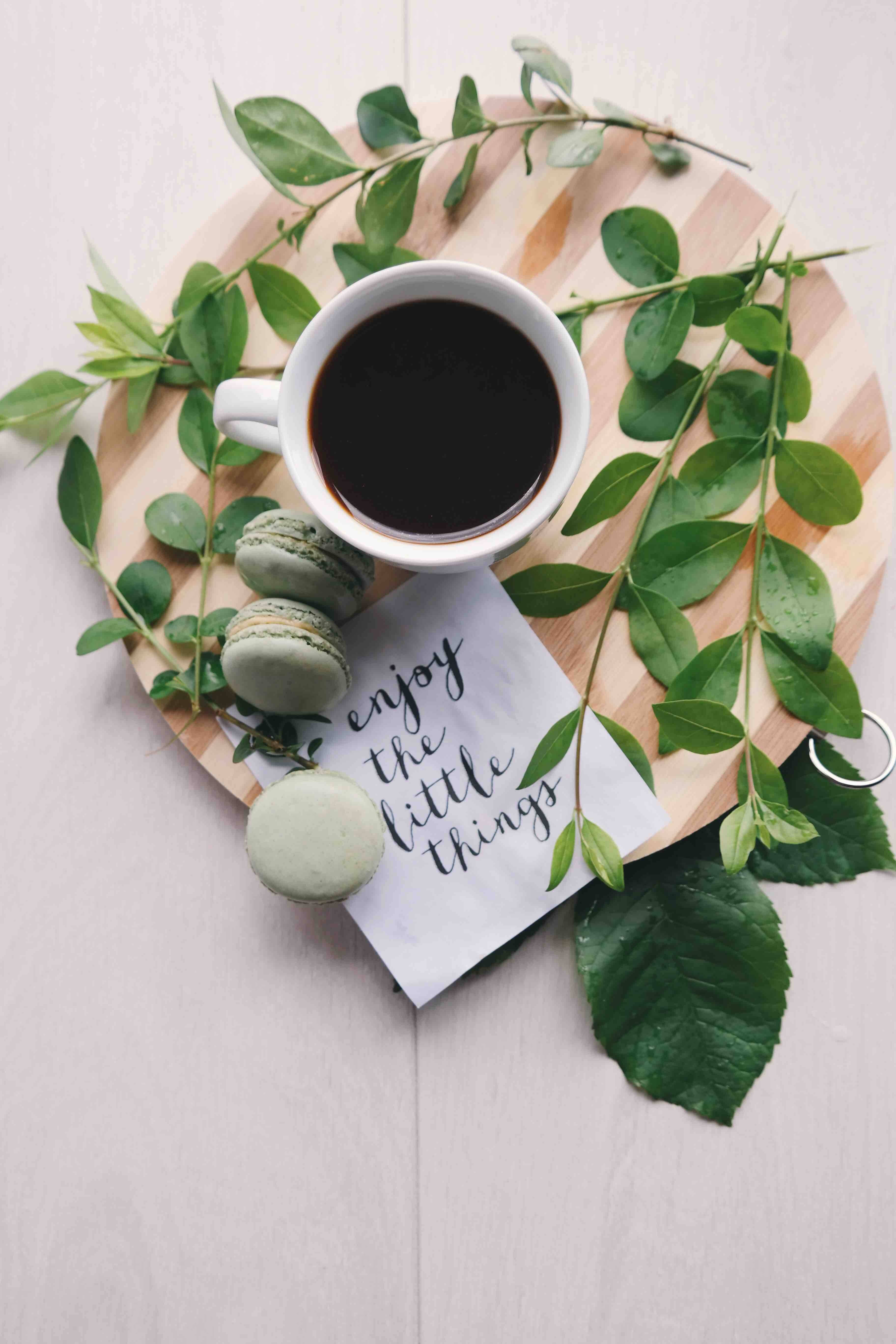 Inspirational Quotes 桌布 壁紙 — 一個白色馬克杯的黑咖啡和三個薄荷綠馬卡龍放在一塊木板上，周圍是新鮮的綠葉和一張手寫便條。