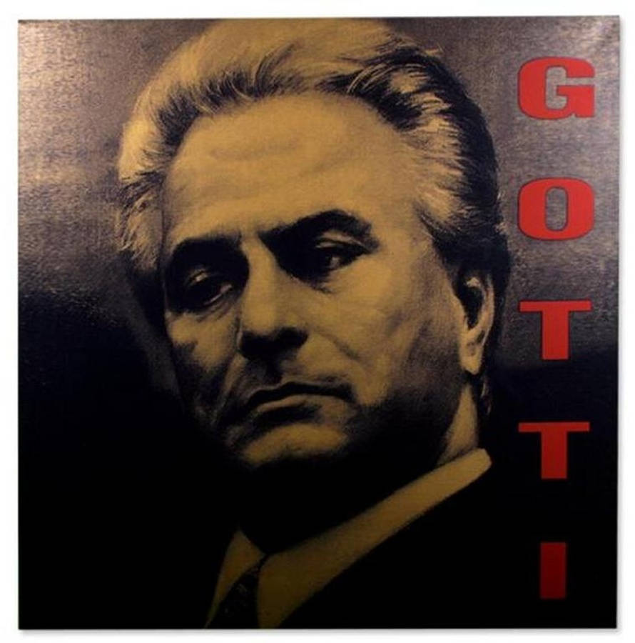 Gotti 桌布 壁紙 — 一個眼神銳利、頭髮花白的男人的粗獷肖像，背景是深色紋理，並有粗體紅色垂直文字拼寫GOTTI。