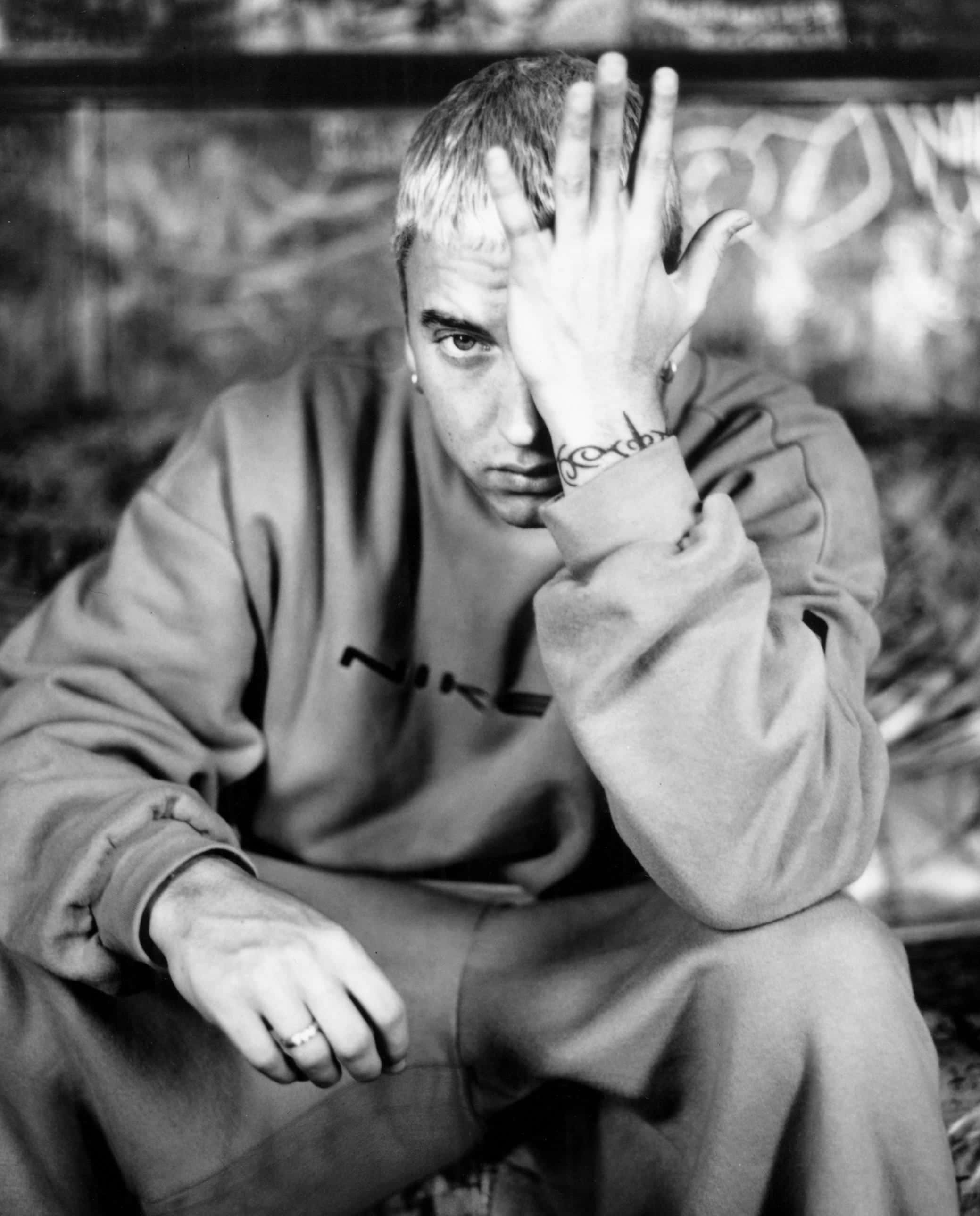 Eminem 桌布 壁紙 — 一個短髮男子穿著Nike運動衫，用手遮住半邊臉的黑白肖像。