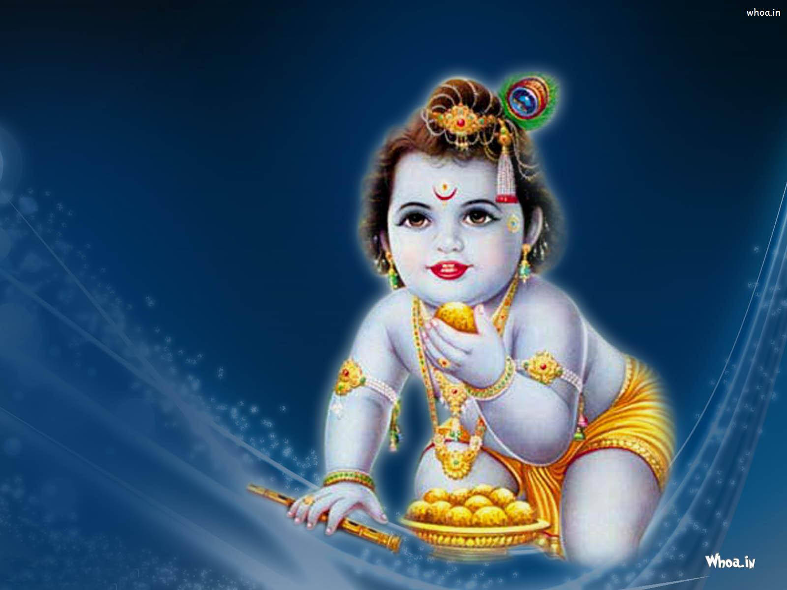 krishna god 桌布 壁紙 — 一個神聖的孩子，藍色皮膚，金色飾物，拿著一盤糖果，背景是發光的藍色宇宙。