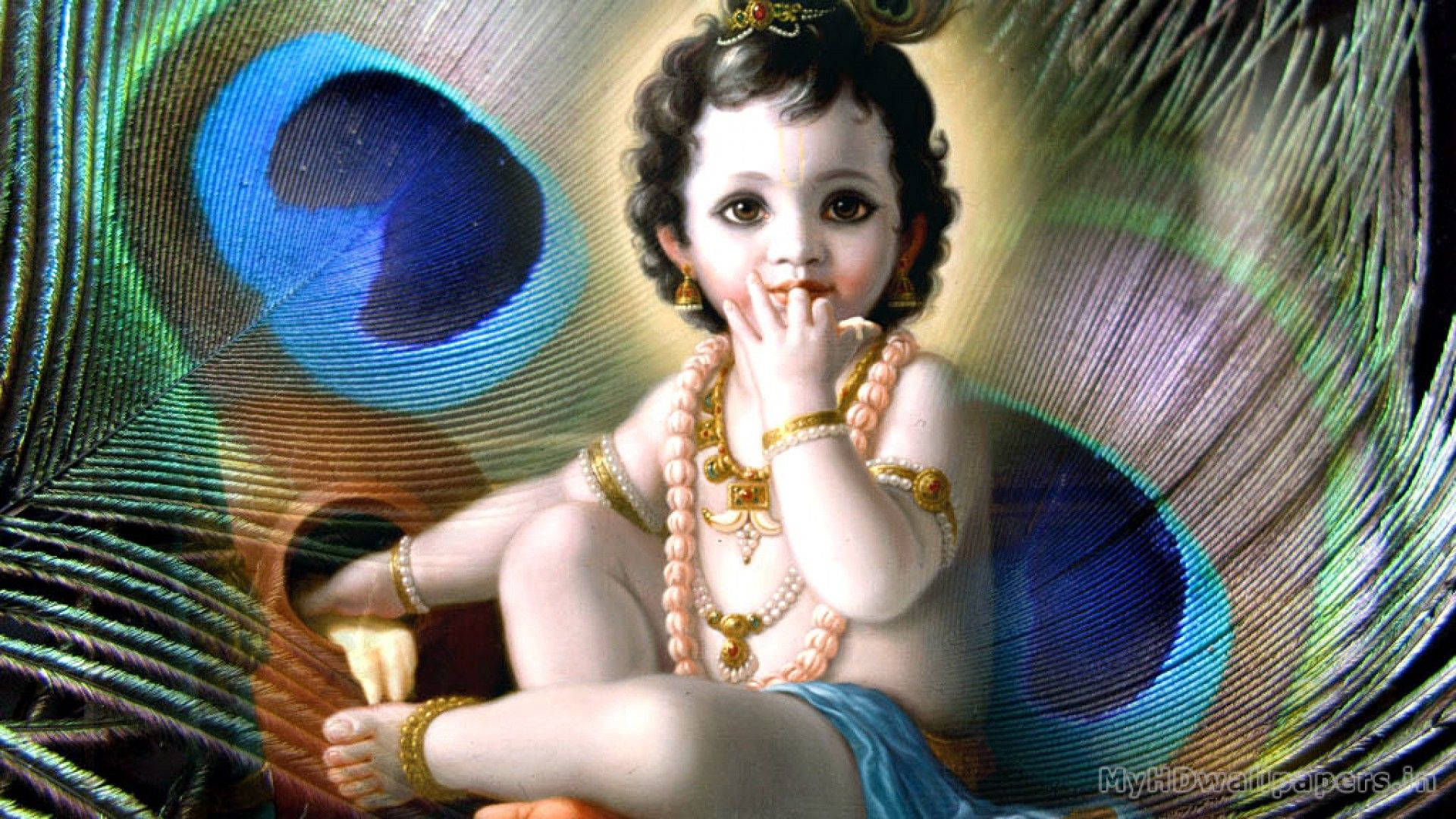 Bal Krishna 桌布 壁紙 — 一個神聖的孩子佩戴著黃金首飾，寧靜地坐在鮮豔的孔雀羽毛中，擁有明亮的藍色眼睛。