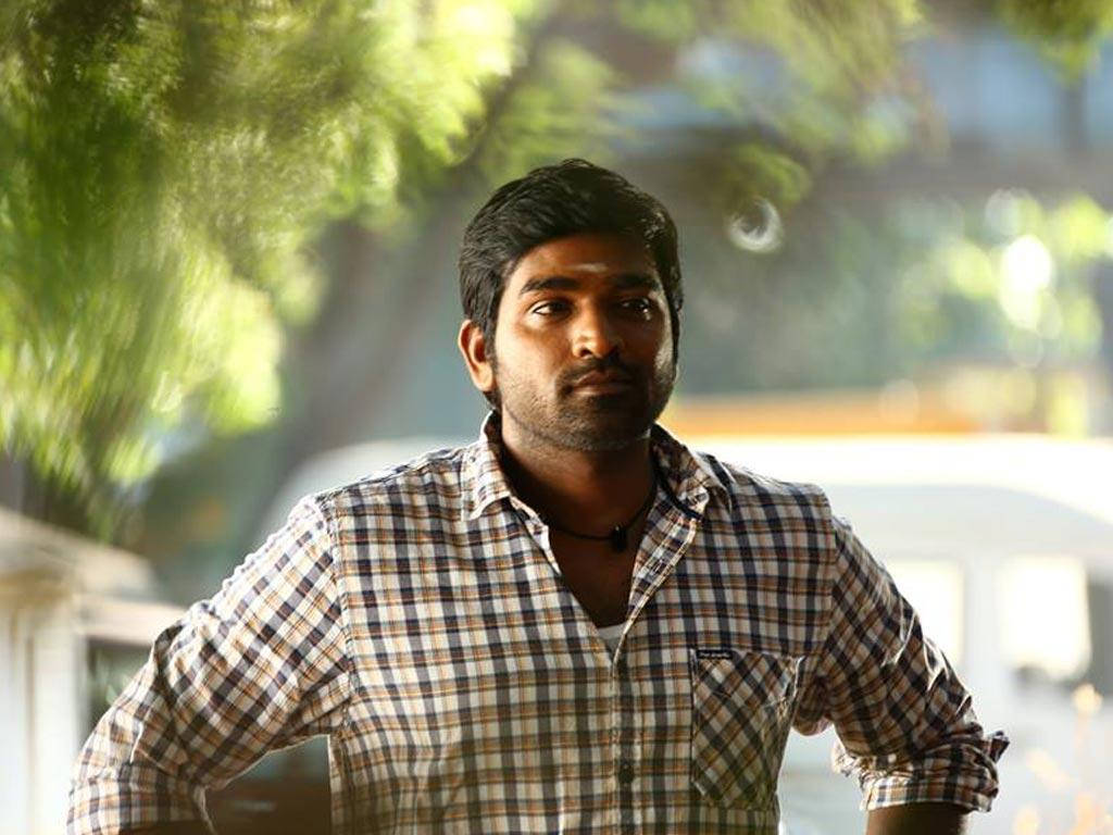 vijay HD 桌布 壁紙 — 一個穿著格仔恤衫的男人自信地站在戶外，陽光穿過他身後嘅綠色樹葉。
