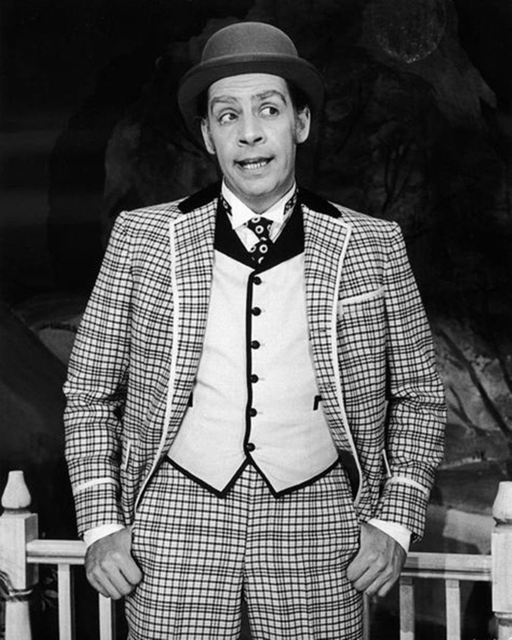 Actor Jerry Orbach Annie Get Your Gun 壁紙 — 一個穿著格紋西裝和圓頂禮帽的男人在黑暗背景下做出驚訝的姿勢。