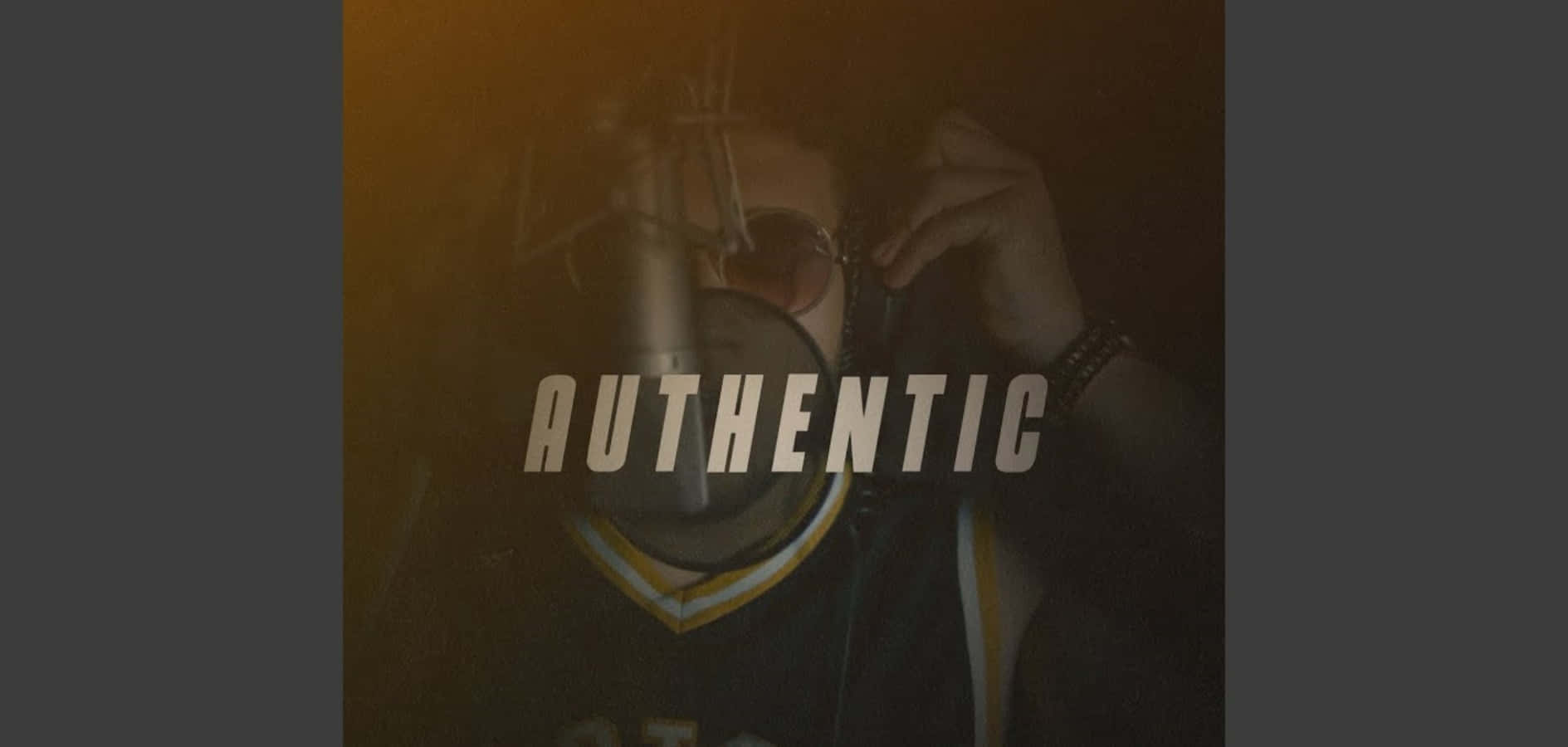 Authentic 桌布 壁紙 — 一個穿著深色球衣嘅人喺溫暖金色燈光下調整太陽眼鏡，上面重疊咗「真實」呢個字。