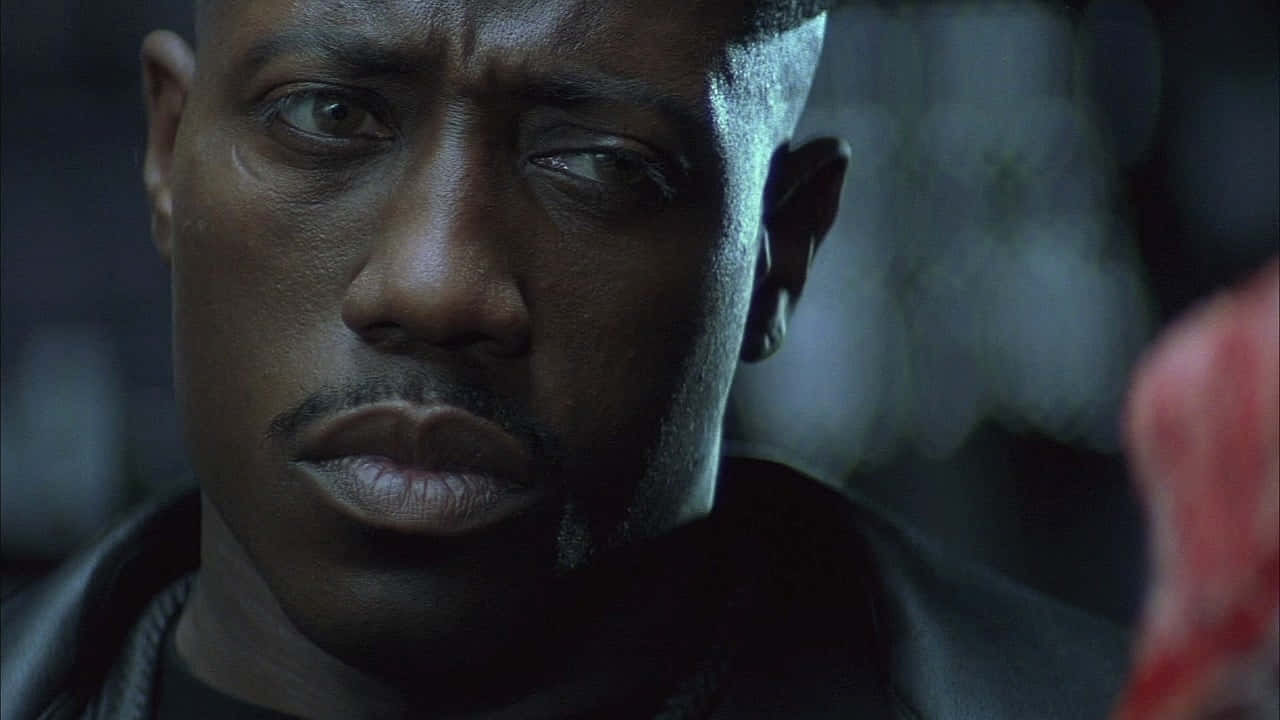 Wesley Snipes 桌布 壁紙 — 一個穿著深色皮褸、表情嚴肅的男人在昏暗藍色燈光下的特寫。