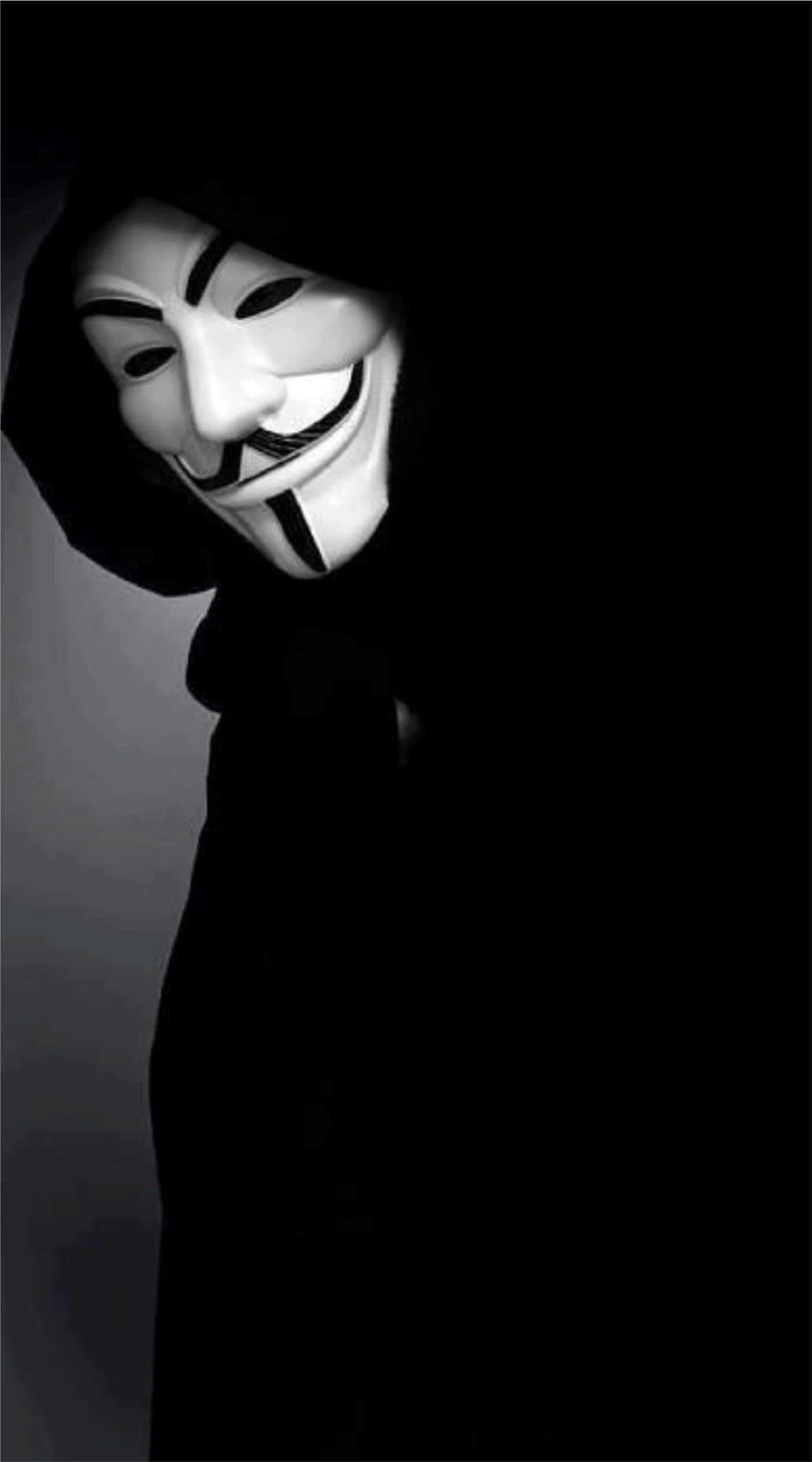 Anonymous 桌布 壁紙 — 一個穿著深色連帽斗篷的人，在純黑色背景上戴著白色蓋伊·福克斯面具。
