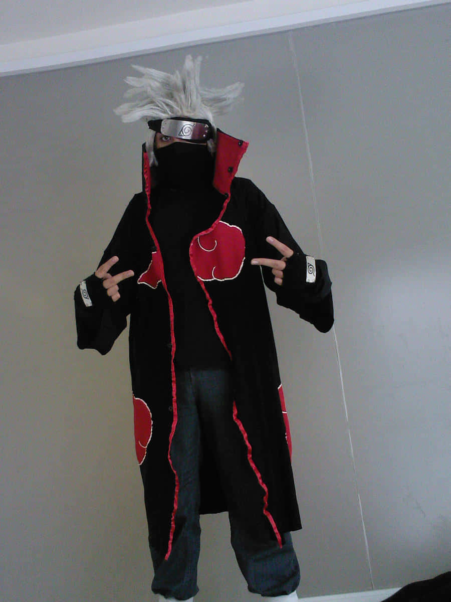 Akatsuki Kakashi 桌布 壁紙 — 一個穿著精細曉角色扮演服裝的人，戴著白色尖刺假髮、黑色斗篷、紅色雲朵符號，並結著手印，在室內擺姿勢。