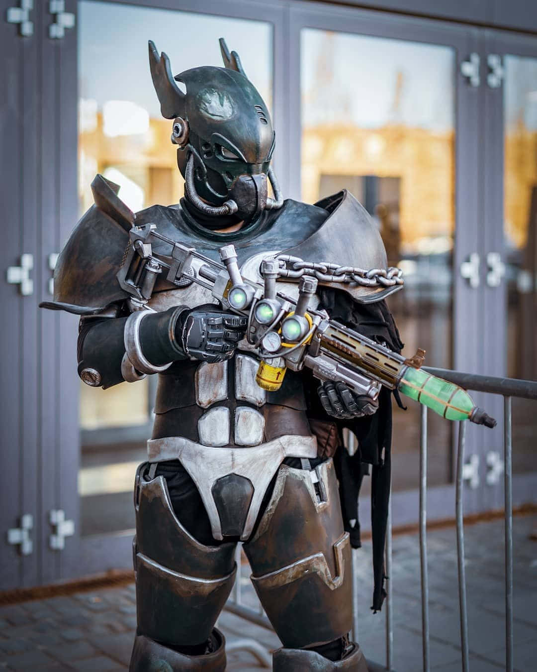 Fallout Brotherhood Of Steel 桌布 壁紙 — 一個穿著精細未來風格盔甲的人，站在玻璃門附近的戶外，手持發光武器。