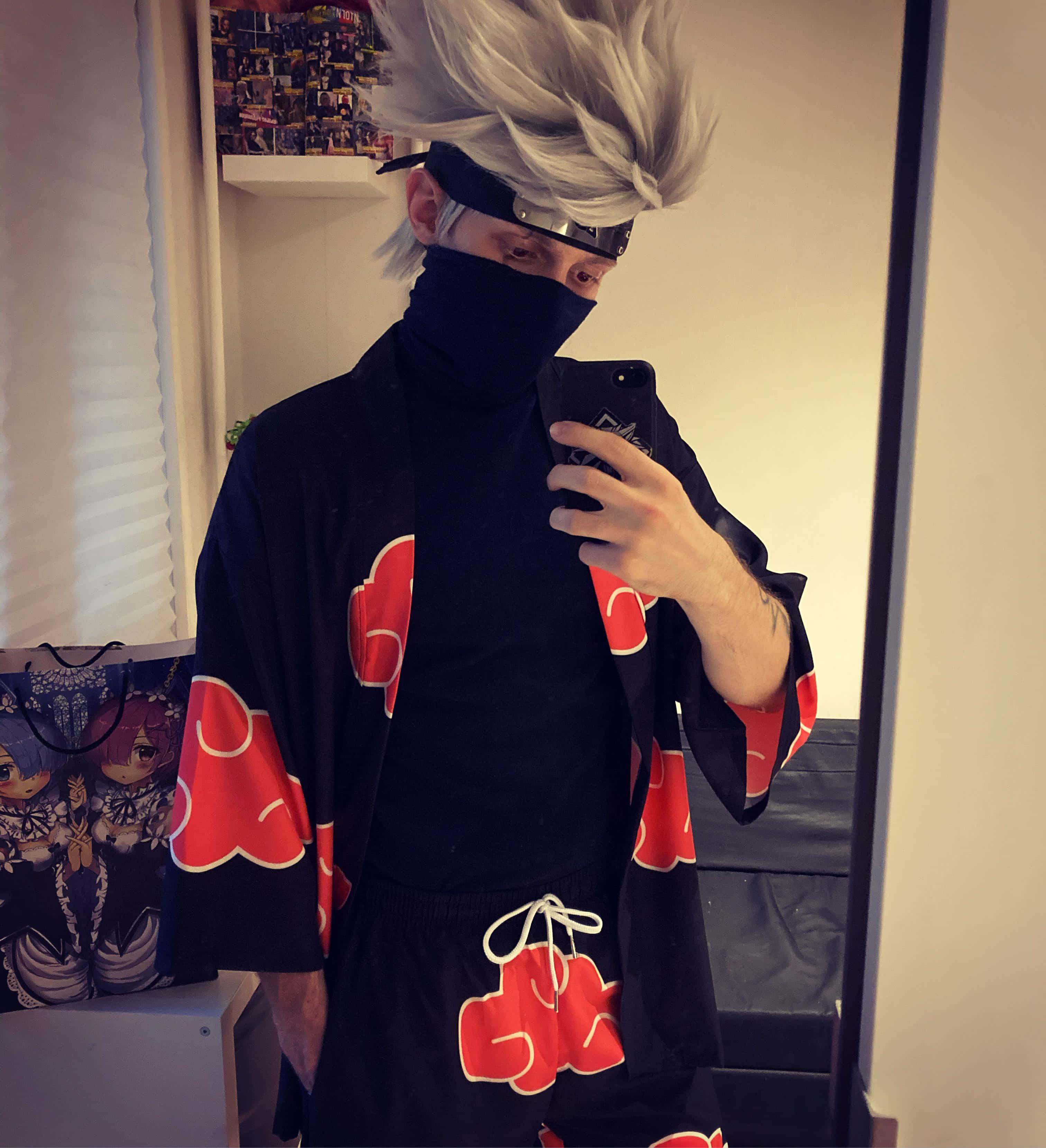 Akatsuki Kakashi 桌布 壁紙 — 一個穿著精細火影忍者cosplay、擁有白色尖刺頭髮和紅色雲紋黑色服裝的人正在鏡子前自拍。