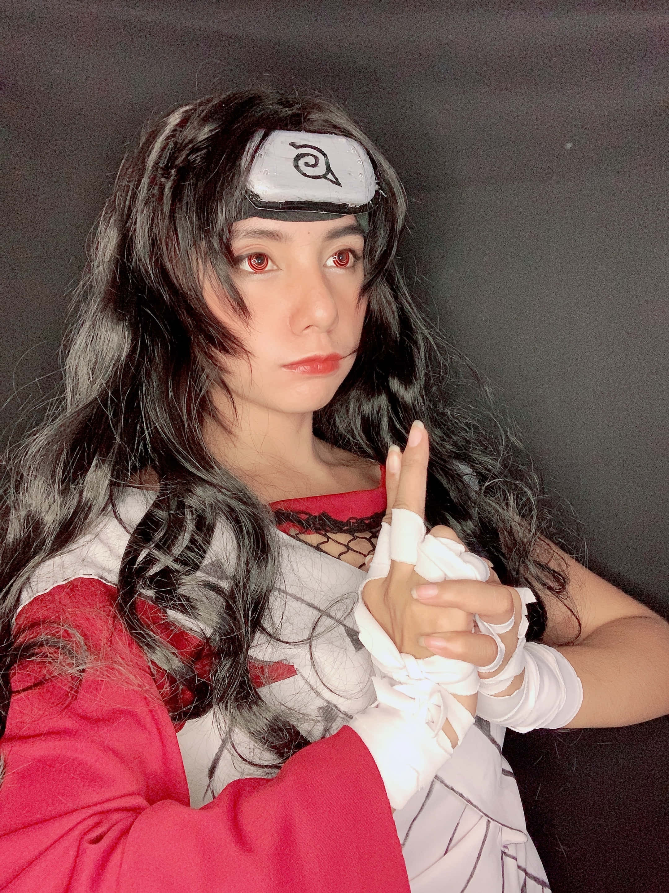 Kurenai Yuhi 桌布 壁紙 — 一個穿著精細火影忍者角色扮演的人，在黑暗背景前戴著頭帶和纏著繃帶的手擺姿勢。