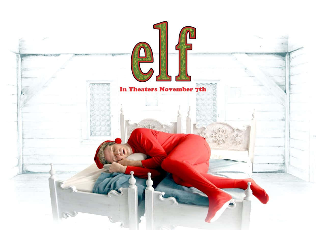Christmas Movie 桌布 壁紙 — 一個穿著紅色精靈套裝的男人在雪地小屋的白色床上安睡，上方有「elf」字樣。