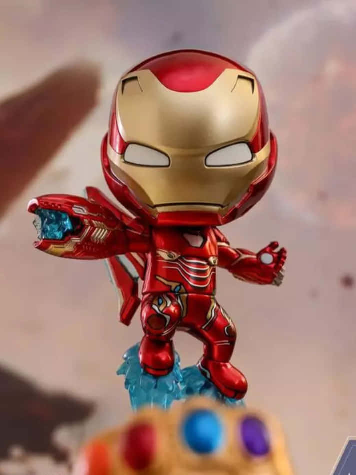 Iron Man Bobbleheads 桌布 壁紙 — 一個穿著紅金盔甲的Q版鐵甲奇俠人偶站在藍色能量底座上，前景是無限手套。