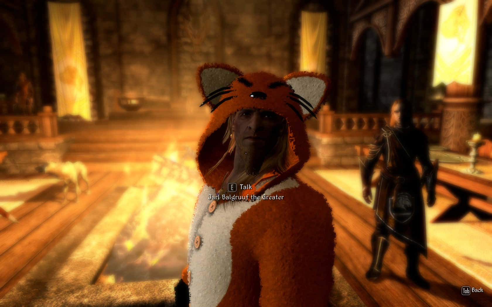Jarl Balgruuf 桌布 壁紙 — 一個穿著老虎主題連帽衫的角色站在一個溫暖照明的中世紀大廳裡，旁邊有熊熊燃燒的壁爐和另一個穿著盔甲的人物。