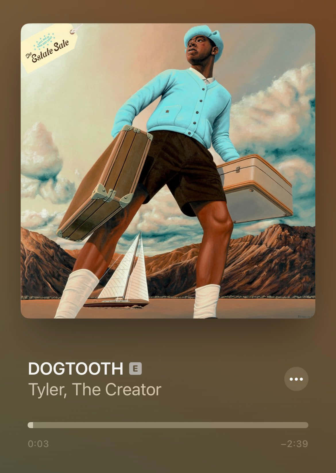 tyler the creator 桌布 壁紙 — 一個穿著藍色開襟毛衣和帽子的男人，站在沙漠景觀中，腳邊有一艘帆船，手提兩個行李箱。