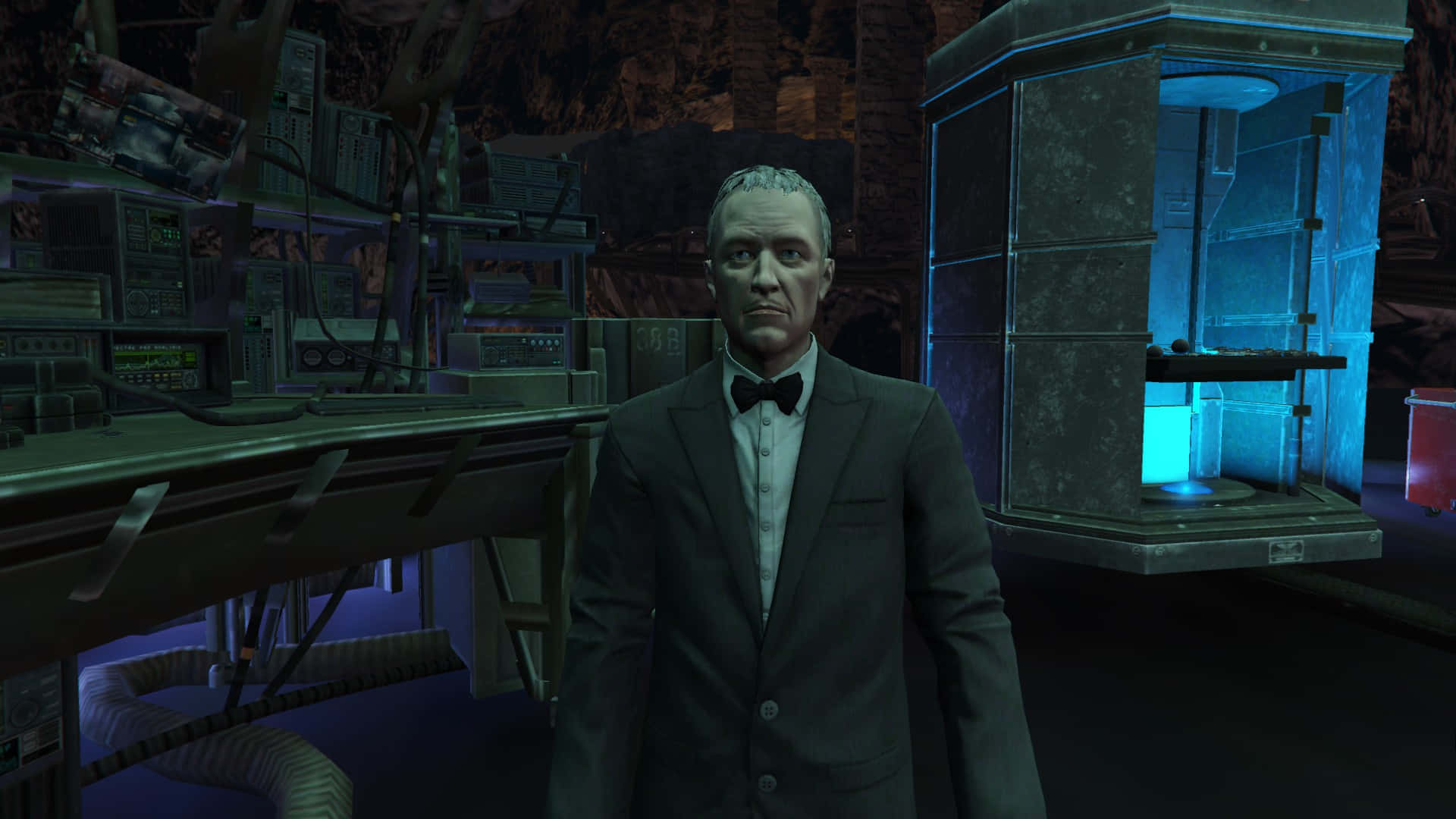 Alfred Pennyworth 桌布 壁紙 — 一個穿著西裝的嚴肅男子站在燈光昏暗、雜亂的實驗室中，周圍有發著藍光的設備和岩石牆壁。