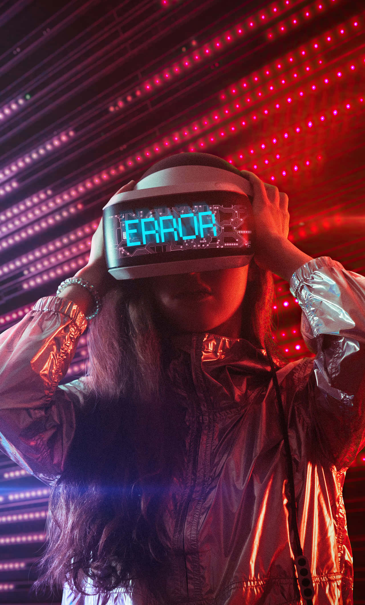 virtual reality 桌布 壁紙 — 一個穿著閃亮外套的人手持VR頭戴式顯示器，在鮮豔的紅色LED網格背景上顯示「ERROR」。
