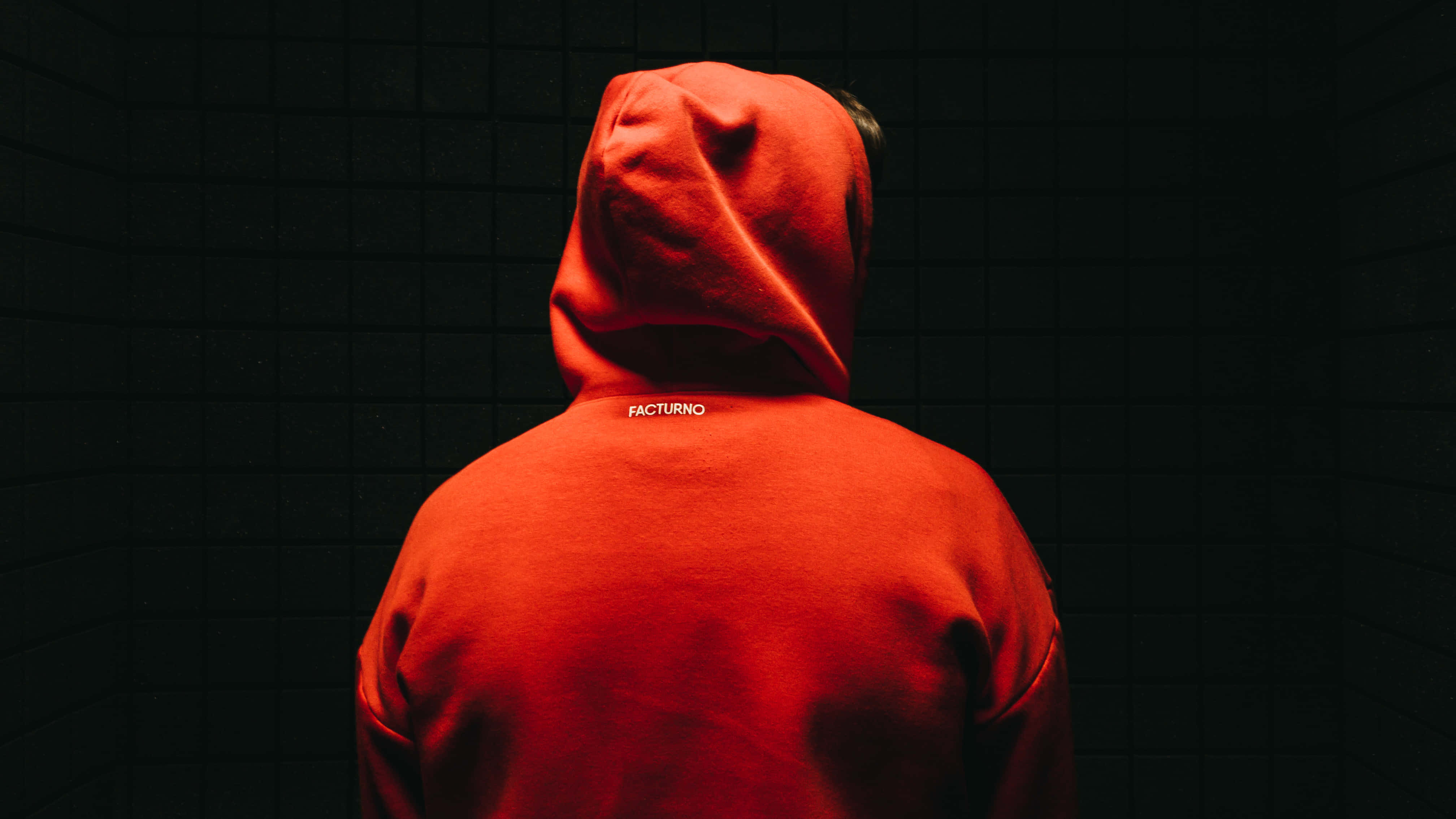 Red Hoodie 桌布 壁紙 — 一個穿著鮮紅色連帽衫的人背對鏡頭，站在燈光昏暗的瓷磚房間裡。