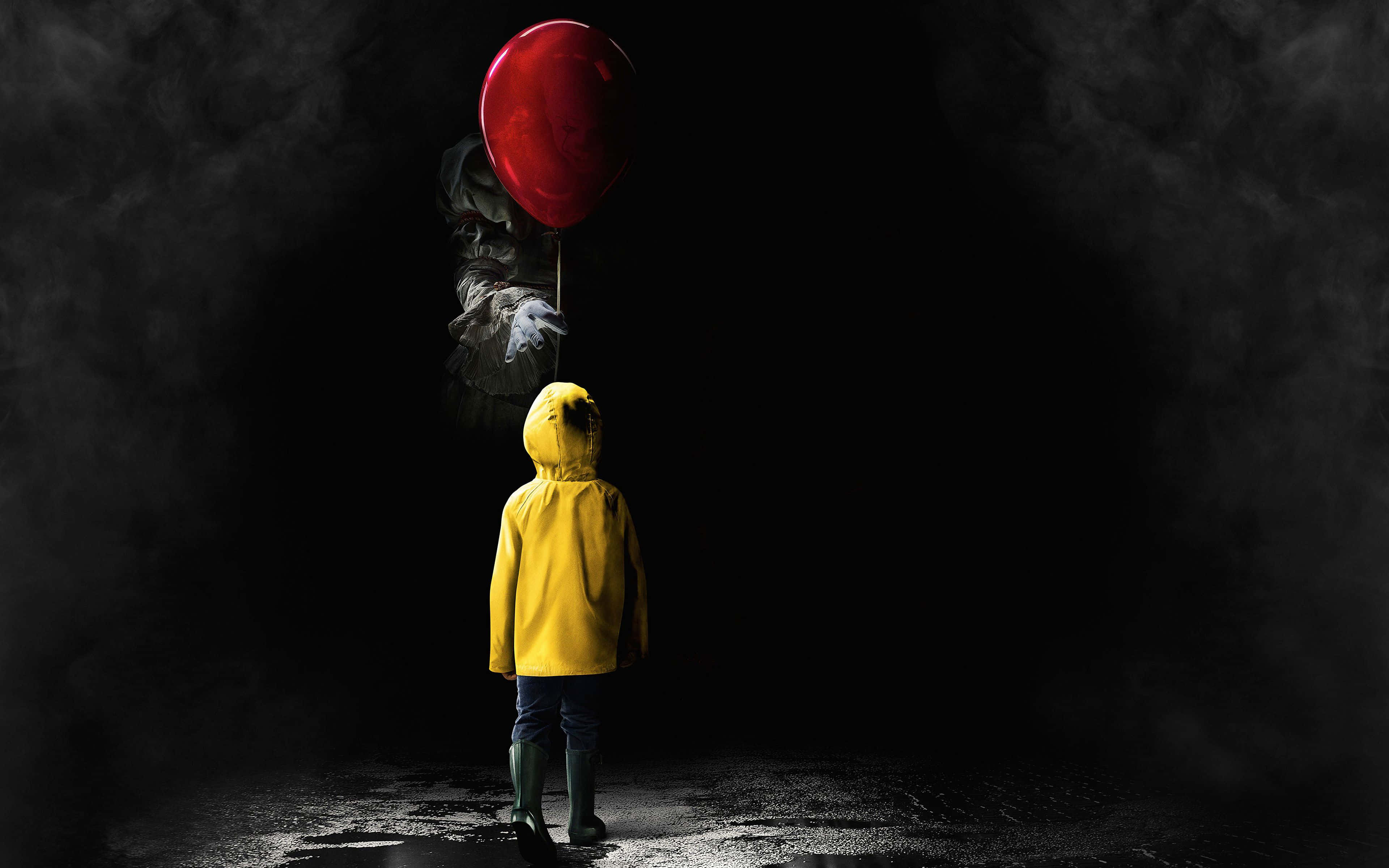 Scary Movies 桌布 壁紙 — 一個穿著黃色雨衣的孩子獨自站在黑暗中，面對一個拿著紅色氣球的可怕小丑。