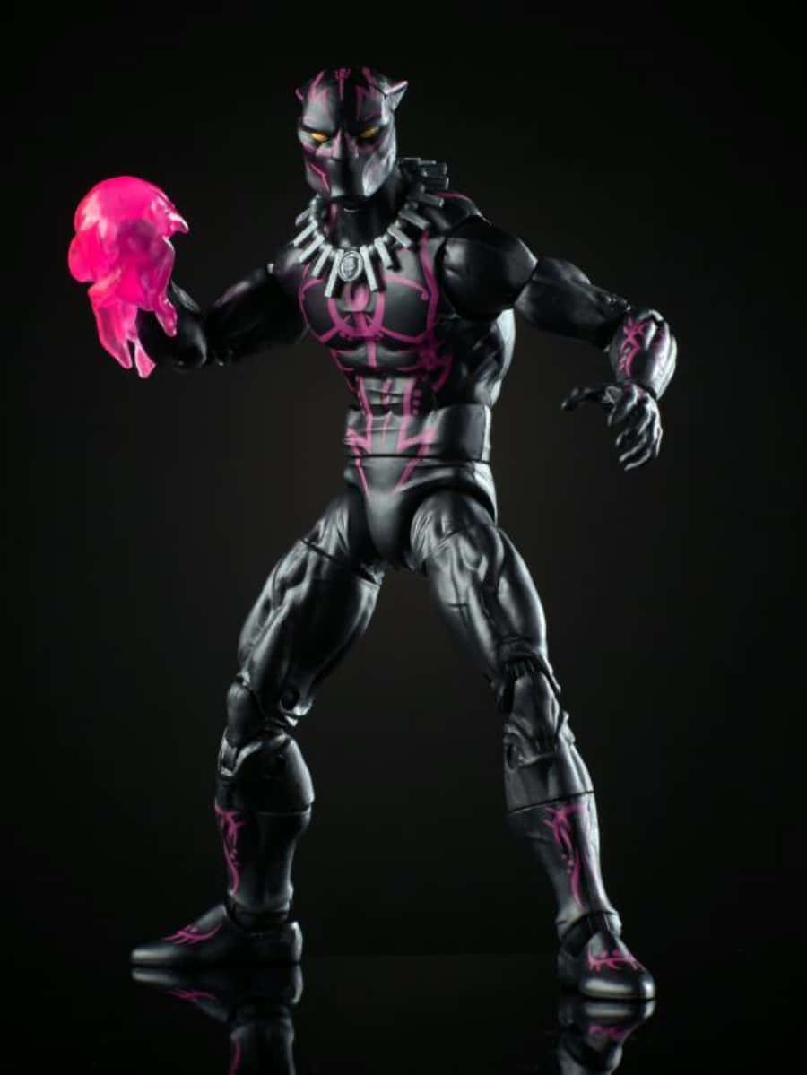 Vibranium Suit 桌布 壁紙 — 一個穿著黑色和粉紅色盔甲的 Black Panther 動作人偶，在黑暗反光背景前手持發光粉紅色頭骨，擺出姿勢。
