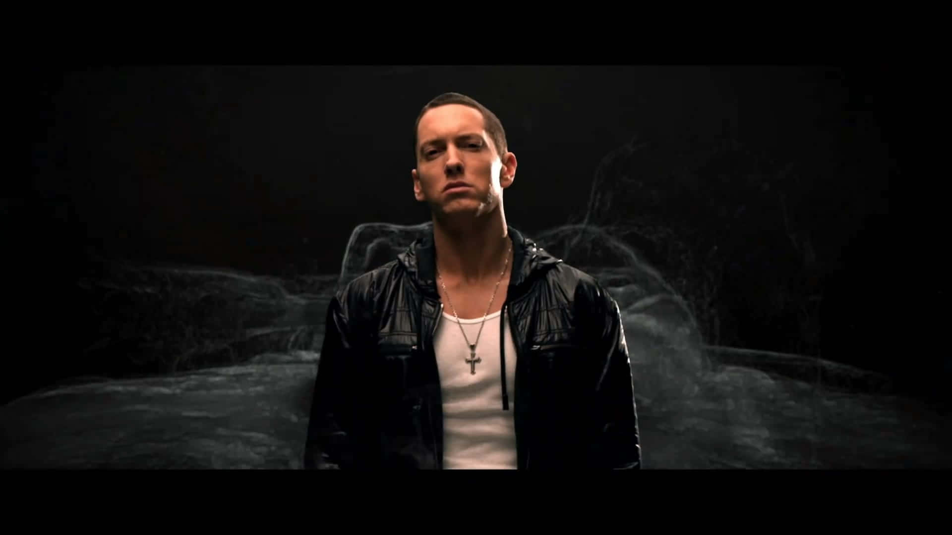 Eminem 桌布 壁紙 — 一個穿著黑色皮褸的男人，站在黑暗煙霧繚繞的背景前，燈光效果戲劇化。